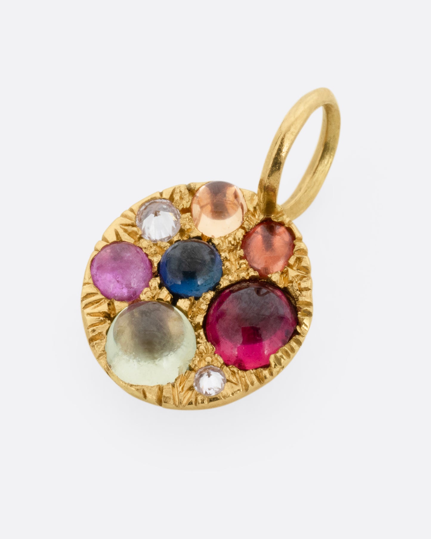 A yellow gold medallion pendant with multicolored sapphire cabochons and reverse set diamonds. Shown lying flat from the front.