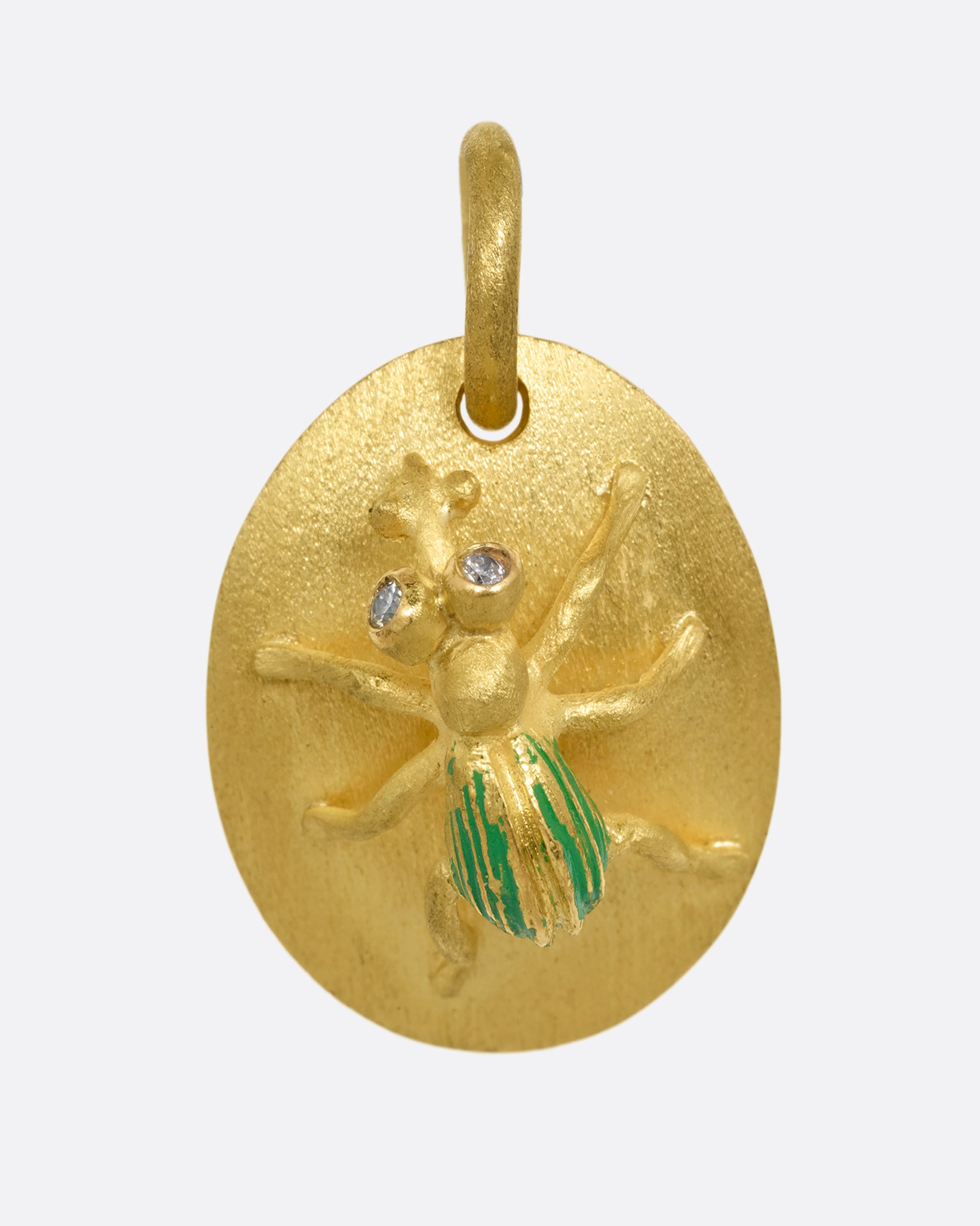 A yellow gold medallion with a diamond eyed bug with green enamel striped wings. Shown from the front.