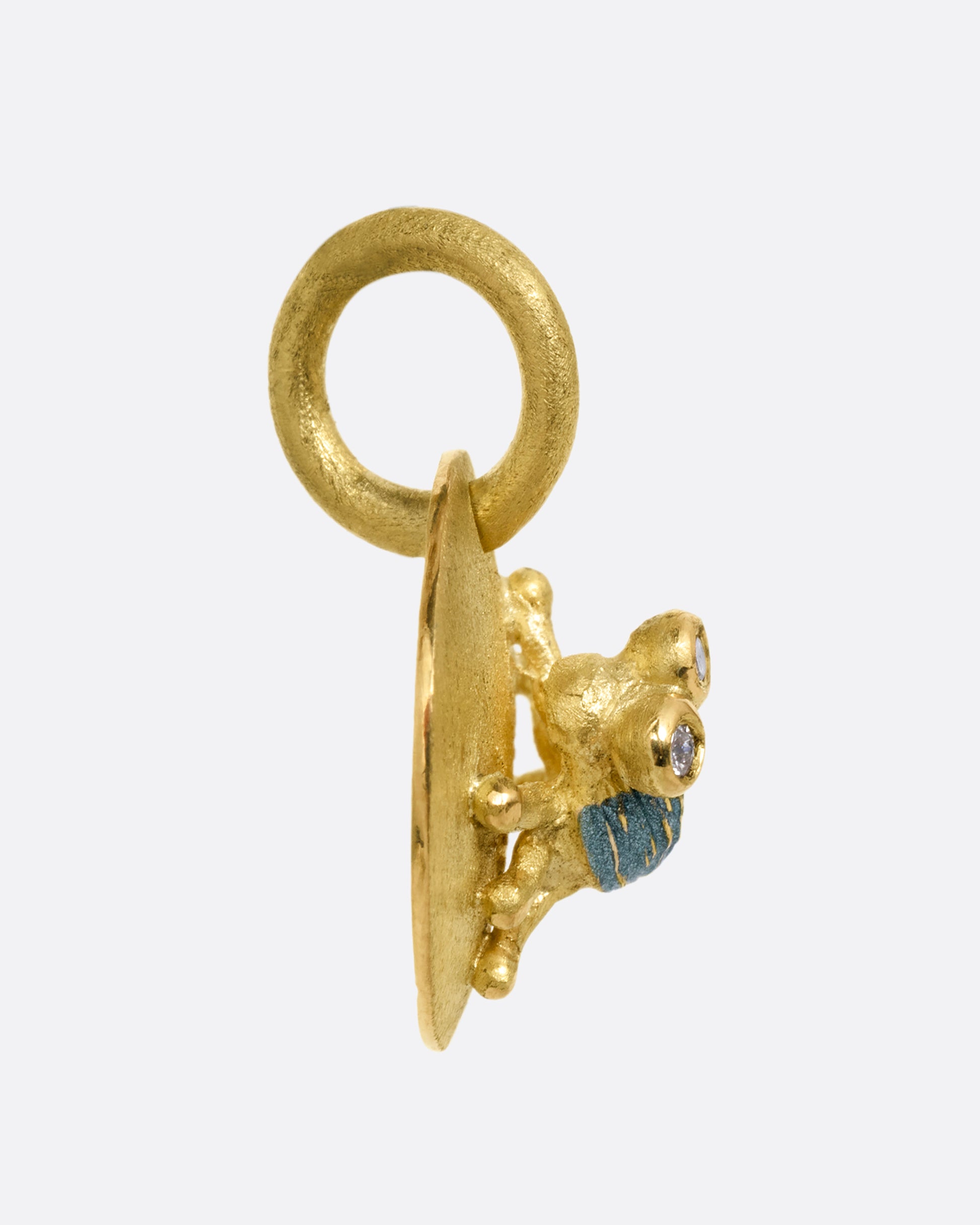 A yellow gold medallion with a diamond eyed bug with blue enamel striped wings. Shown from the side.