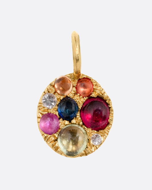 A yellow gold medallion pendant with multicolored sapphire cabochons and reverse set diamonds. Shown from the front.