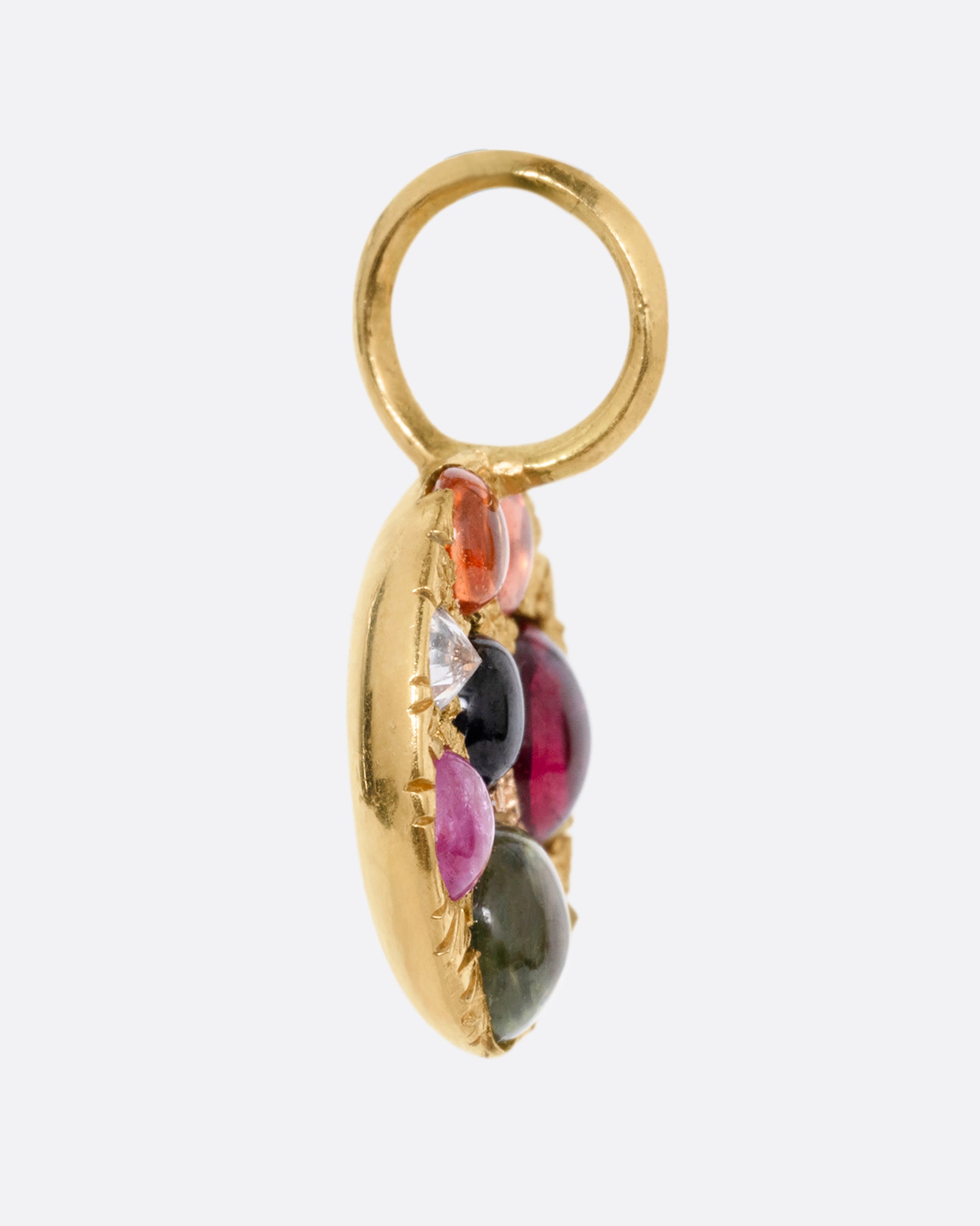 A yellow gold medallion pendant with multicolored sapphire cabochons and reverse set diamonds. Shown from the side.