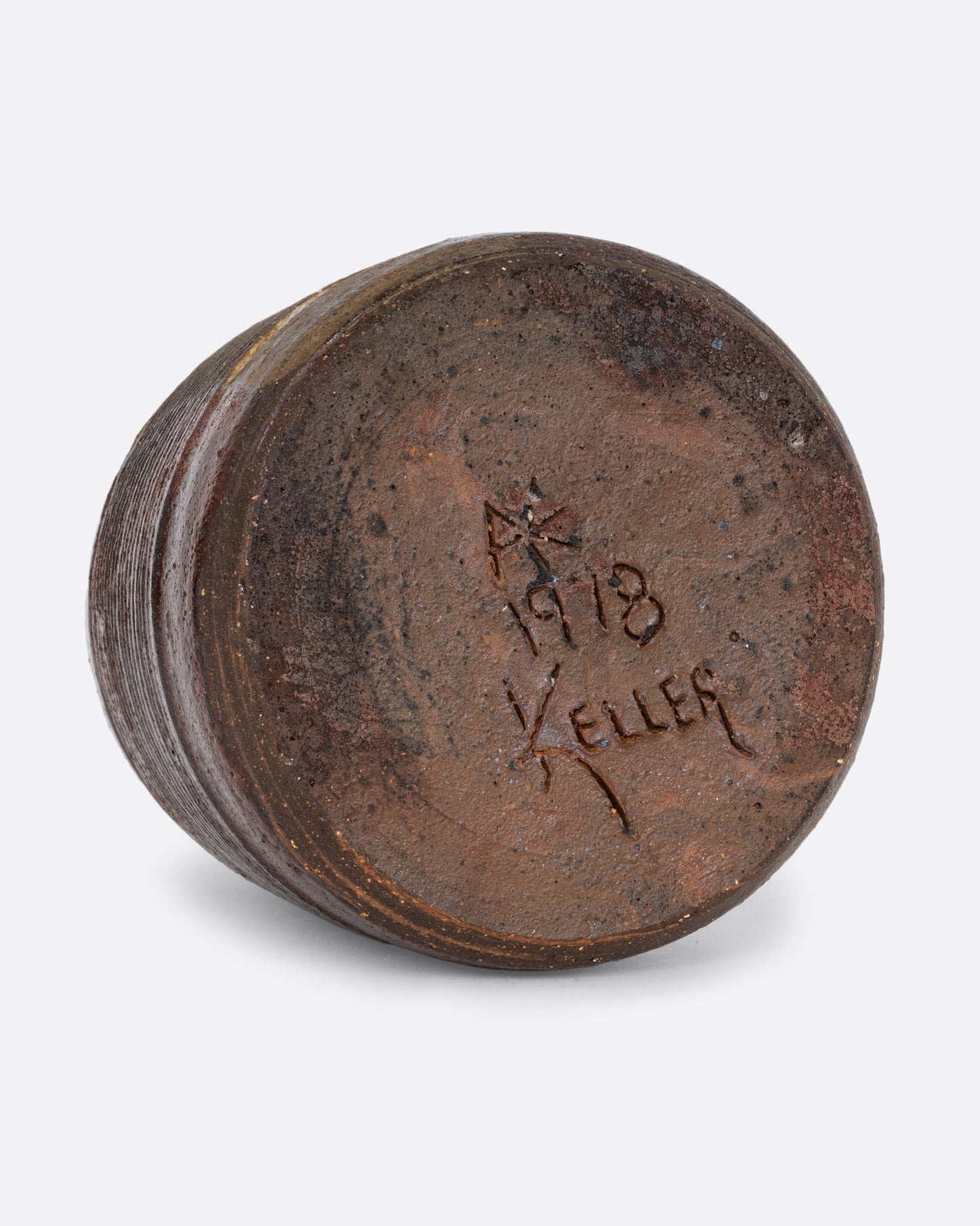 A vase with a brown split contrast glaze and ribbed texture. The artist's signature and 1978 are carved on the bottom. Shown on its side from the bottom.