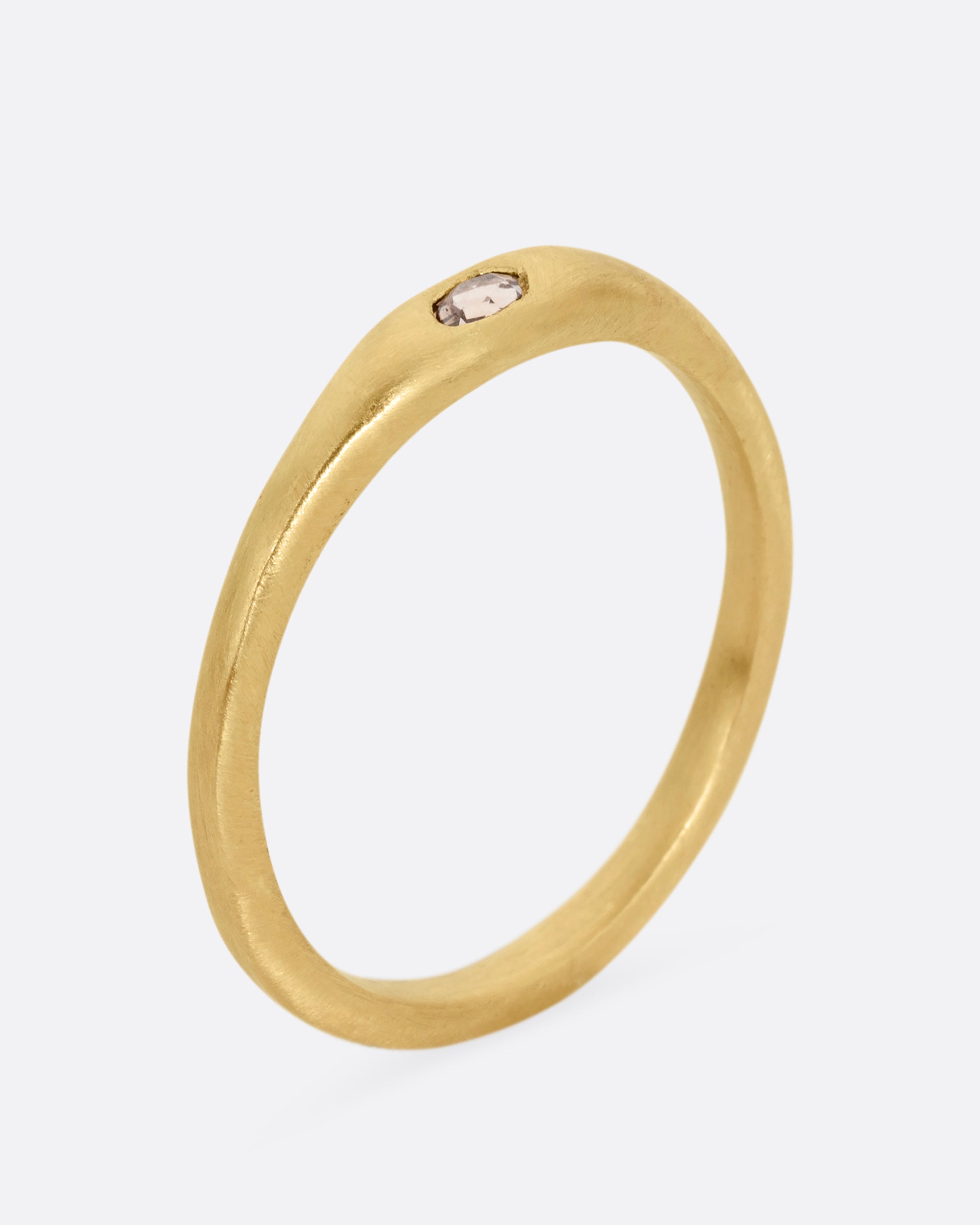 A yellow gold ring with a rose cut diamond. Shown standing up from the side.