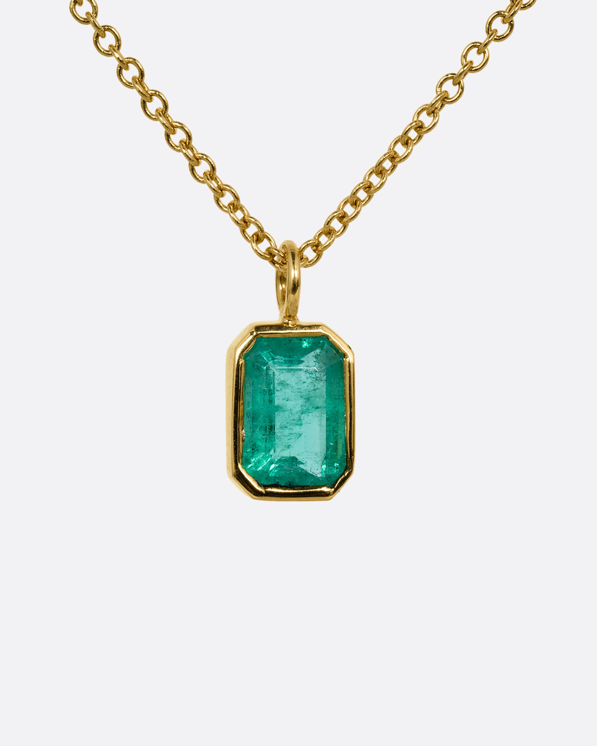A yellow gold cable chain necklace with a bezel set Zambian emerald. Shown from the front.
