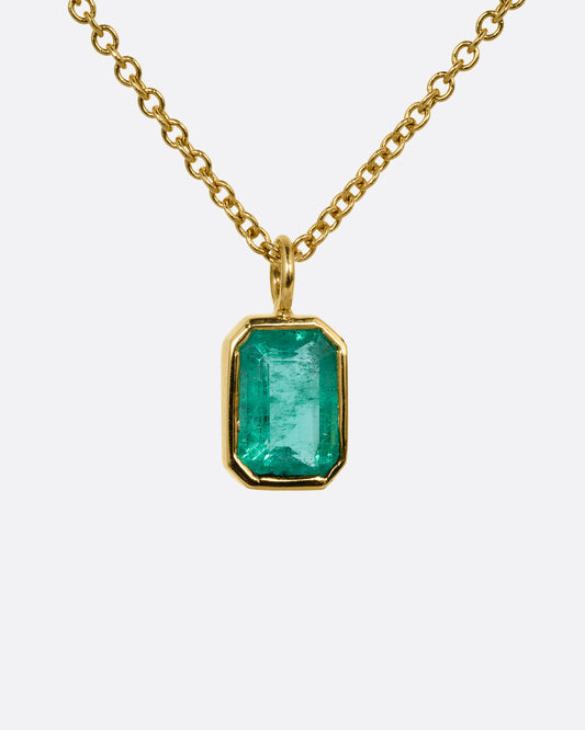 A yellow gold cable chain necklace with a bezel set Zambian emerald. Shown from the front.