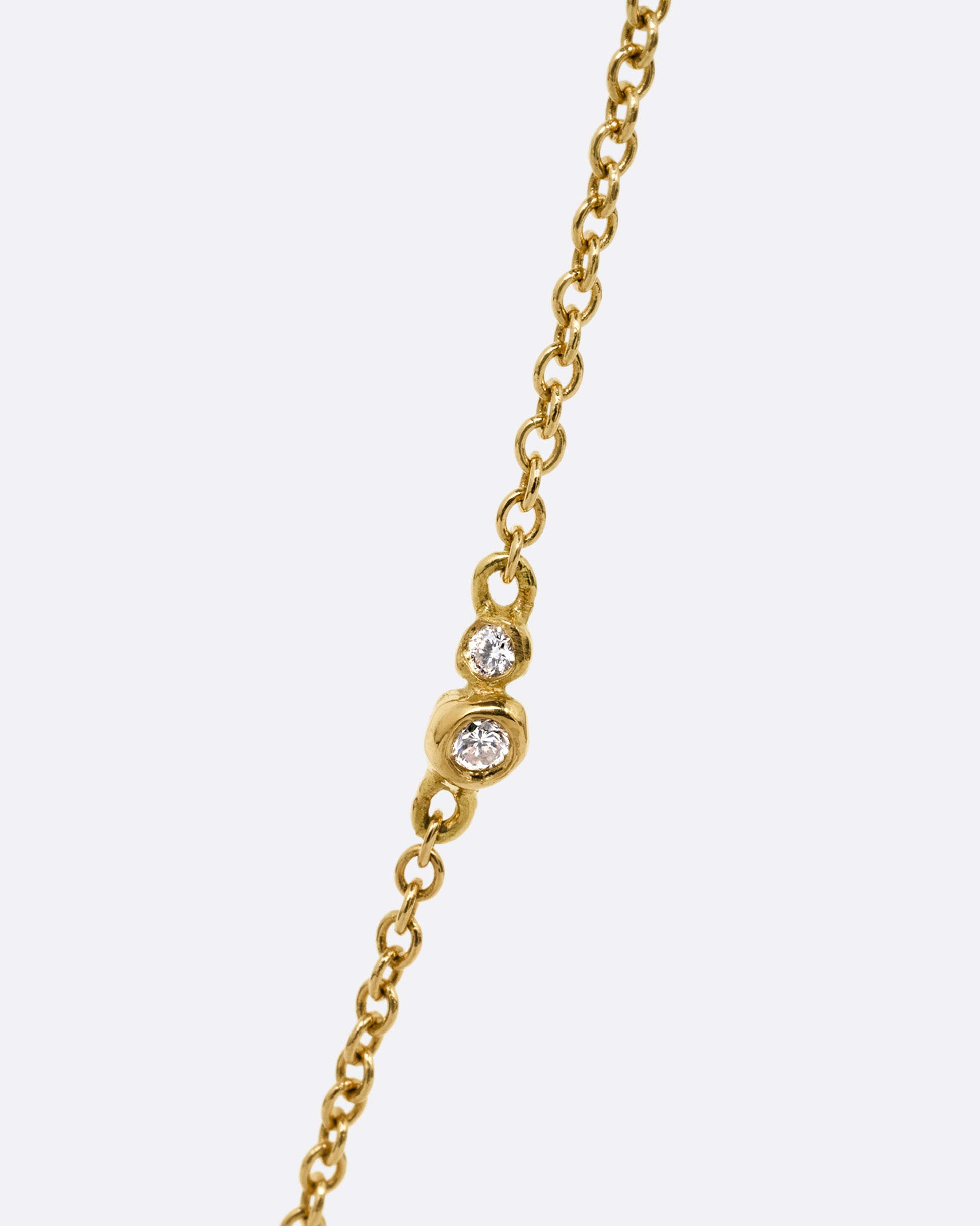 A yellow gold cable chain with two bezel set diamonds shown from the front at an angle.