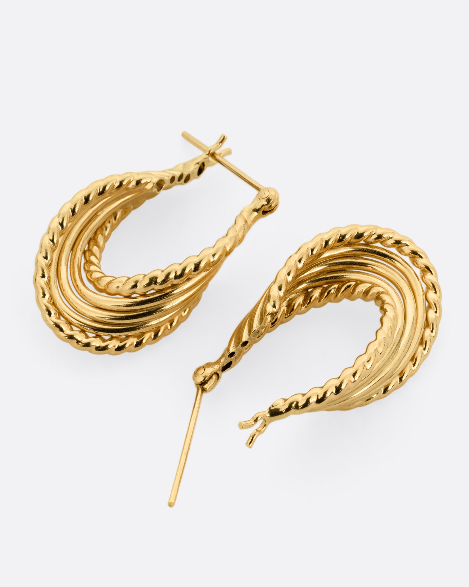 A pair of yellow gold earring with layers of twisted loops and click tops. One earring is shown lying flat from the bottom, the other is shown open lying flat from the top.