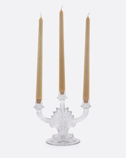 A clear glass candelabra with three holders, shown from the front with candles in each arm.