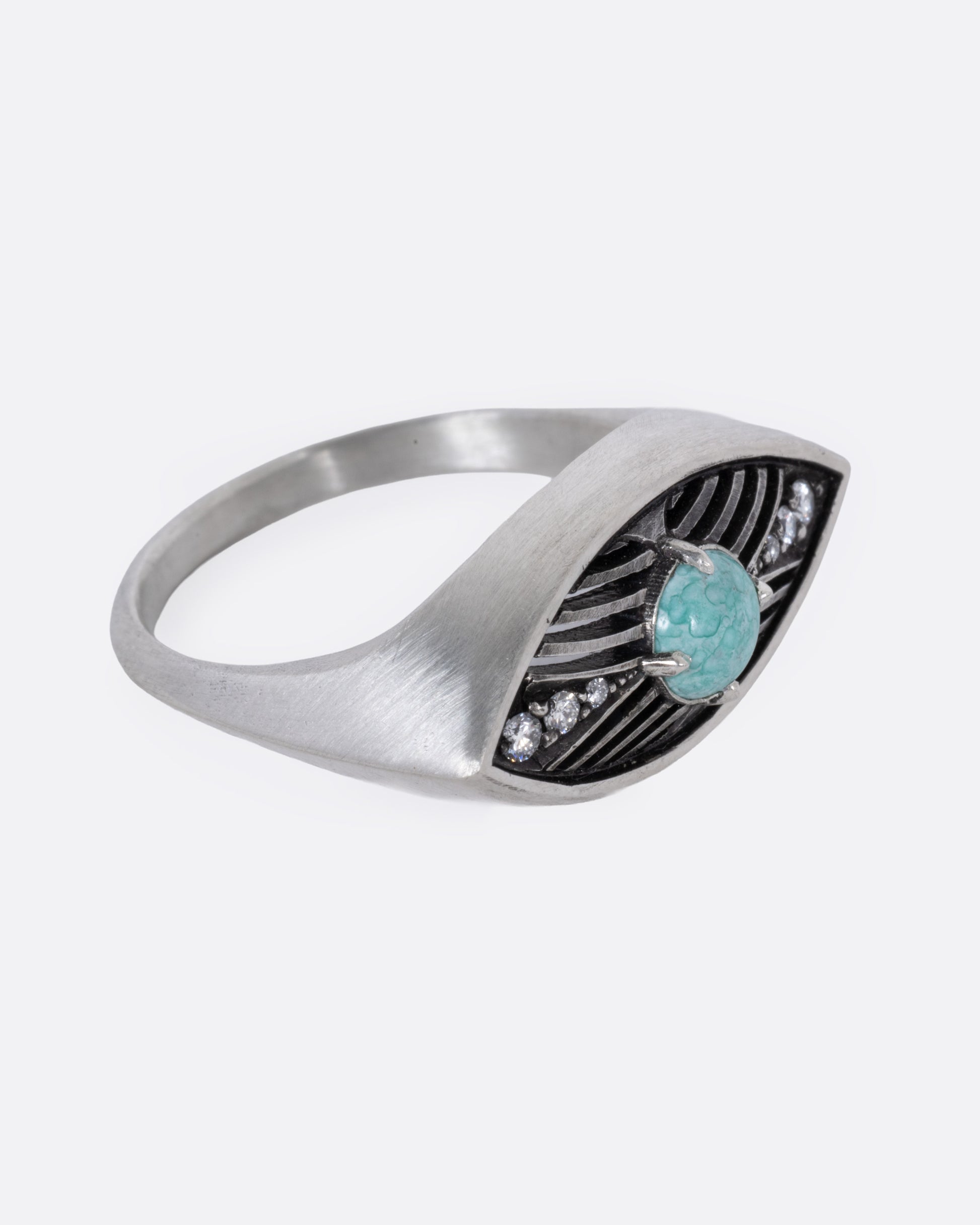 A silver eye shaped ring with a marbled Mexican turquoise cabochon and diamond details, shown from the side.