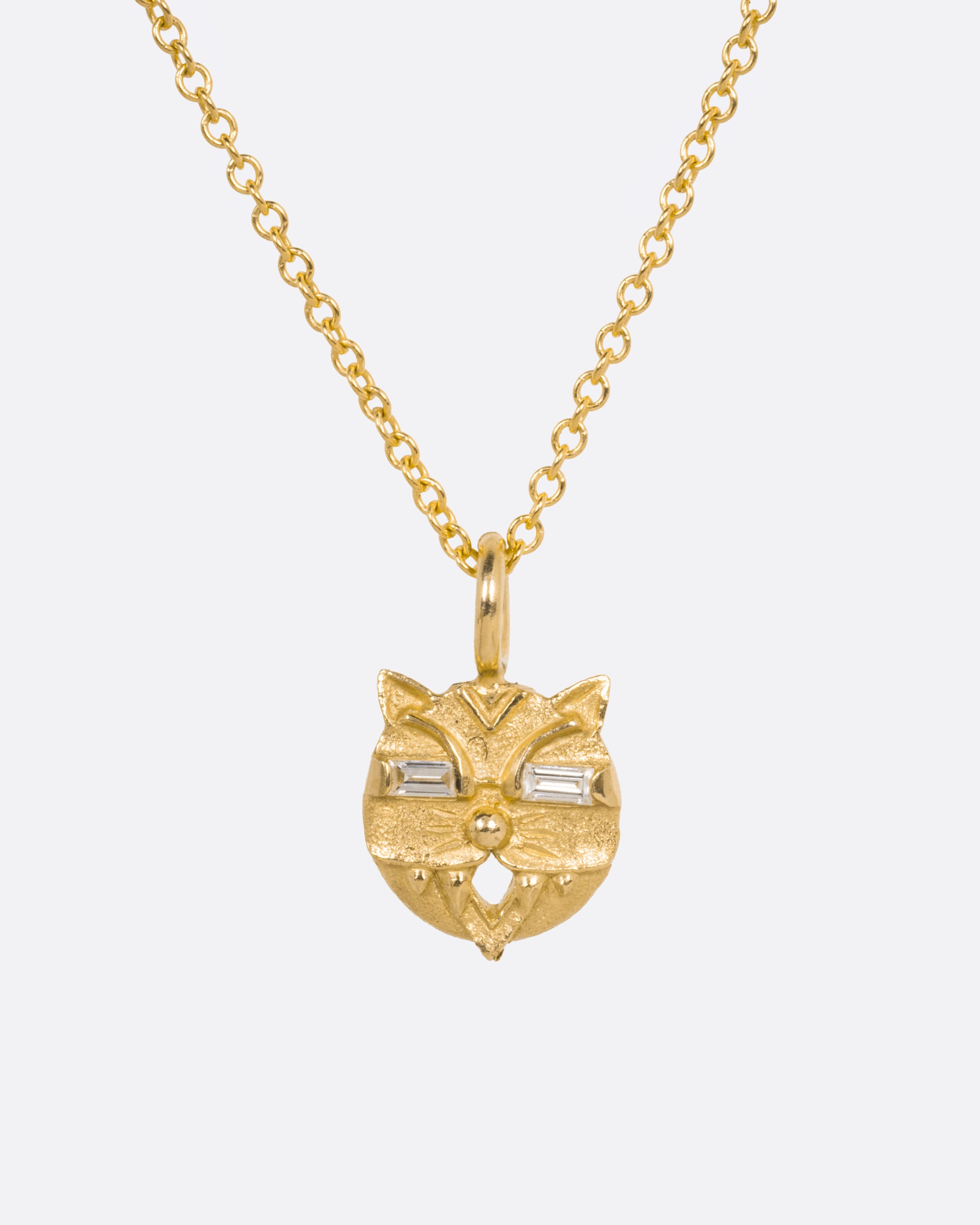A yellow gold cable chain necklace with a cat head shaped pendant with baguette diamond eyes, shown from the front.