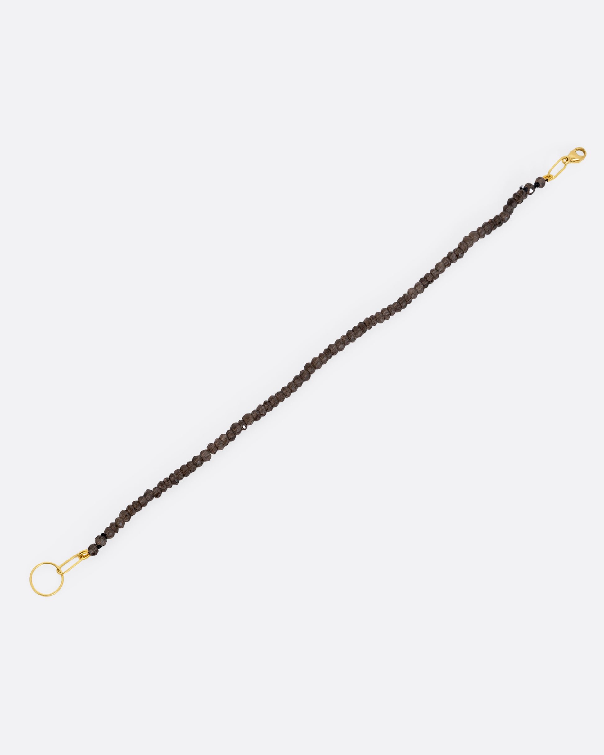 A beaded smoky quartz bracelet with a yellow gold clasp. Shown from the front.
