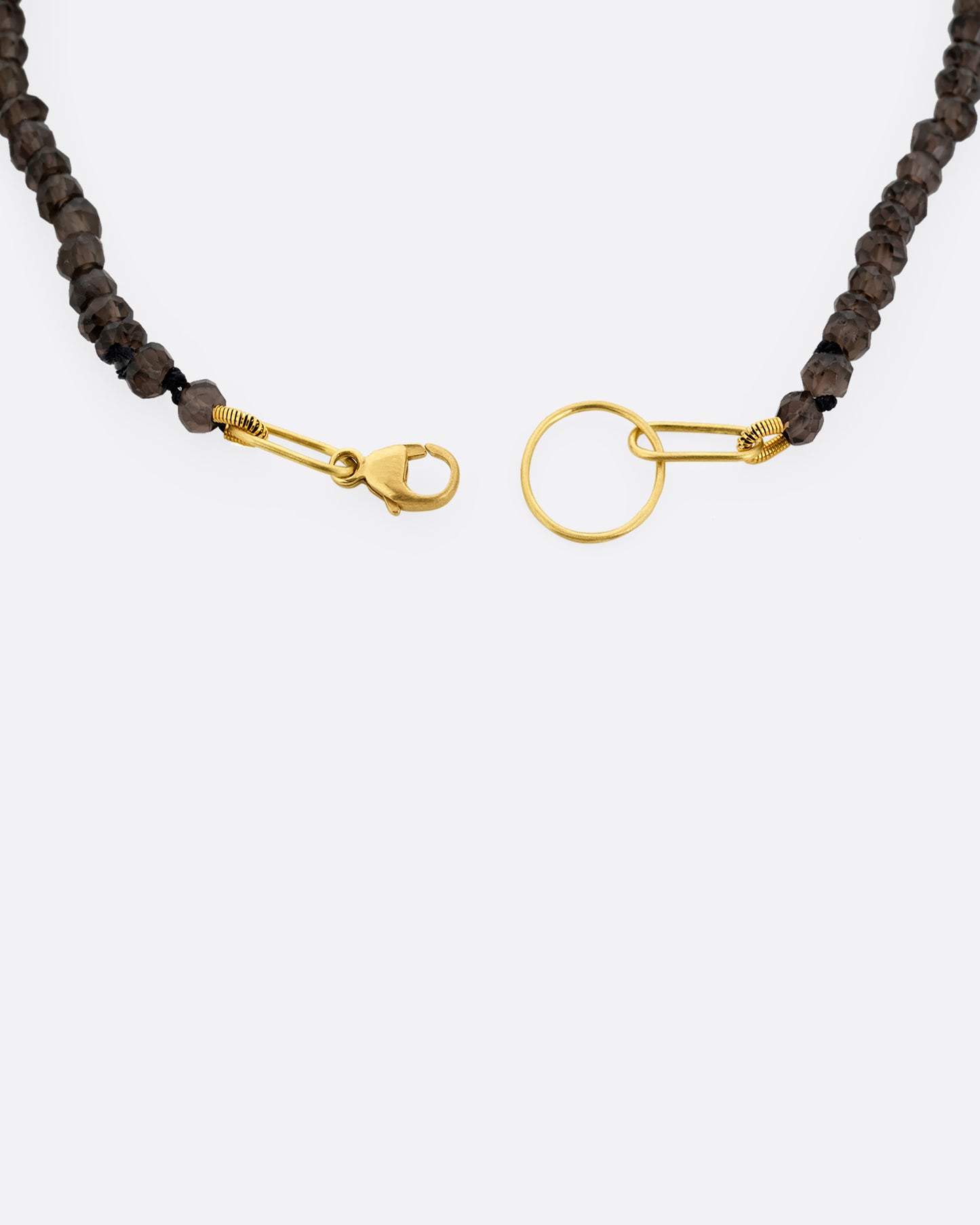 A close up of a beaded smoky quartz bracelet with a yellow gold clasp.