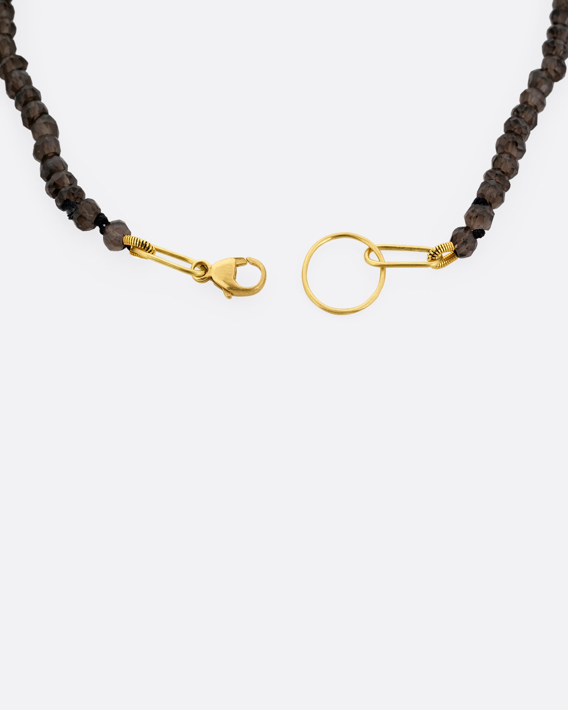 A close up of a beaded smoky quartz bracelet with a yellow gold clasp.