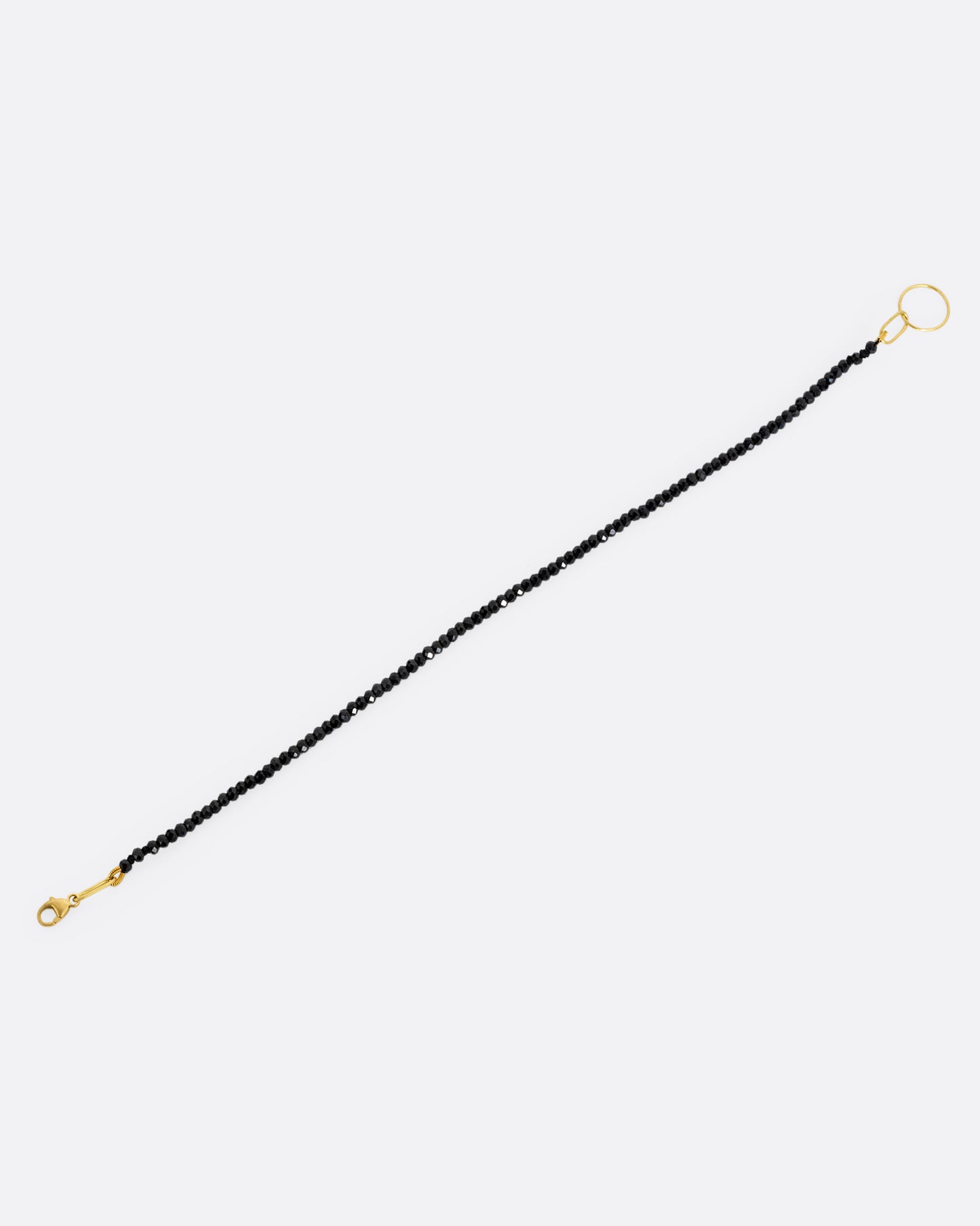 A black spinel beaded bracelet with a yellow gold clasp. Shown from the front.