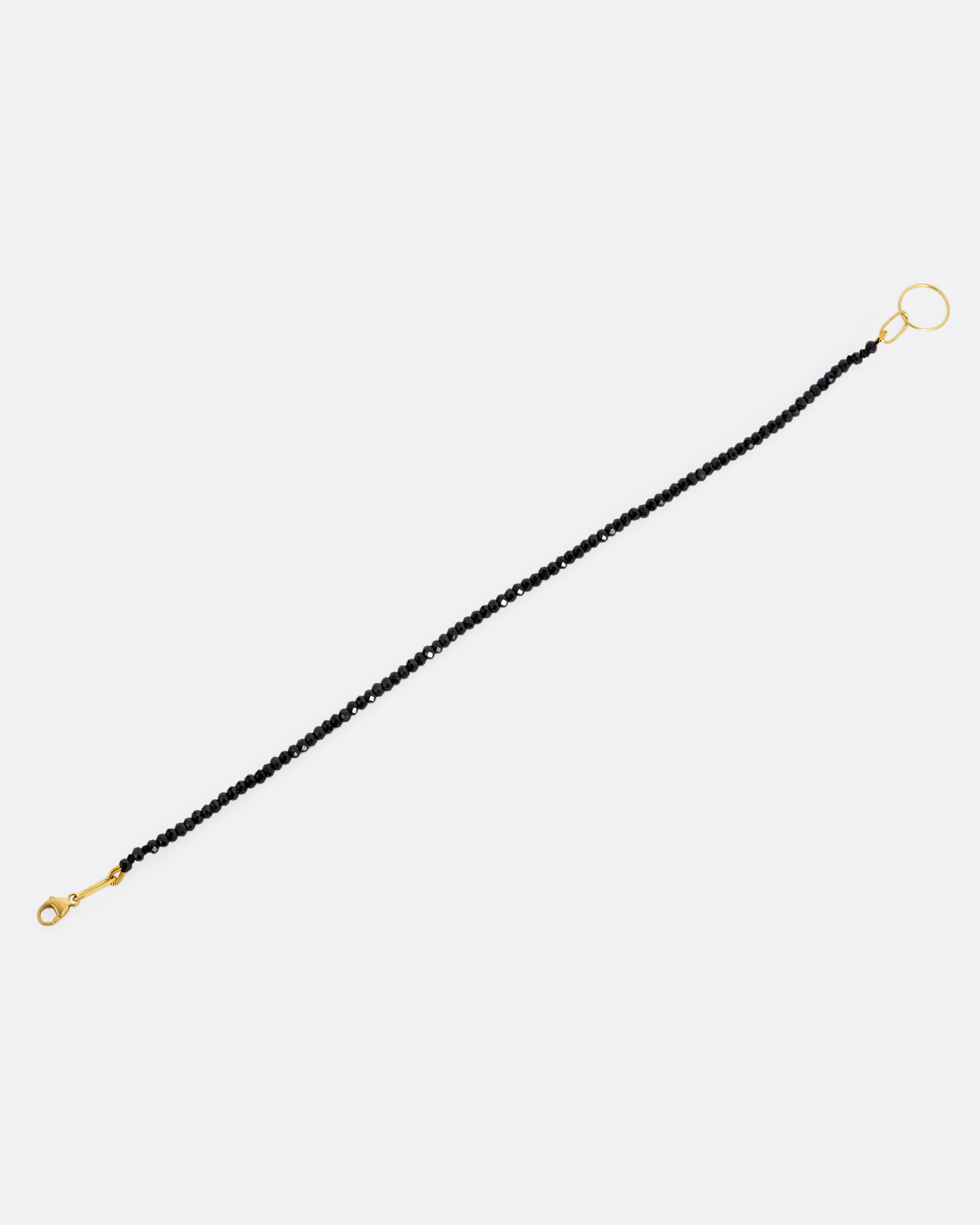 A black spinel beaded bracelet with a yellow gold clasp. Shown from the front.