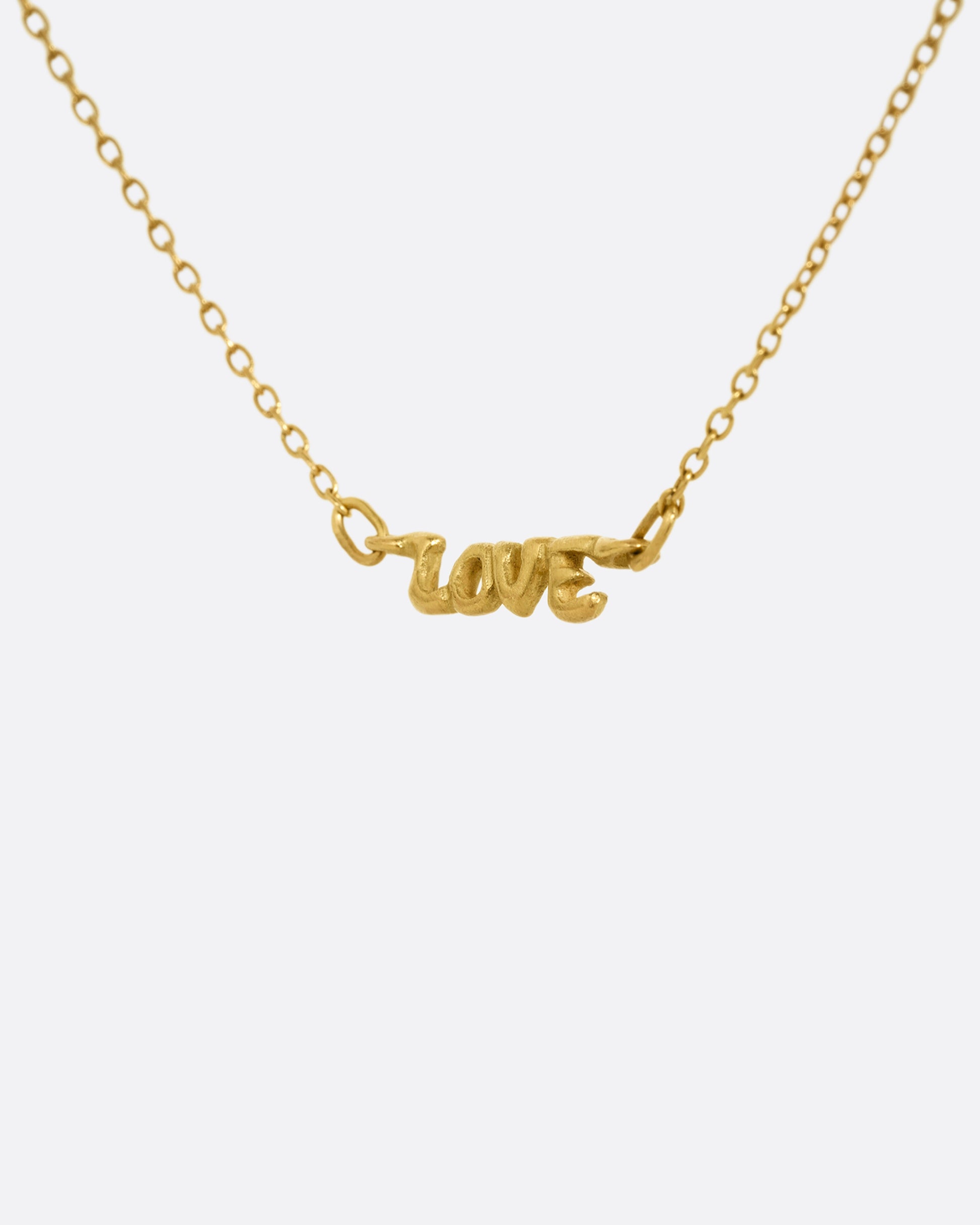 A yellow gold cable chain necklace with a 'LOVE' charm at the center. Shown at an angle from the front.