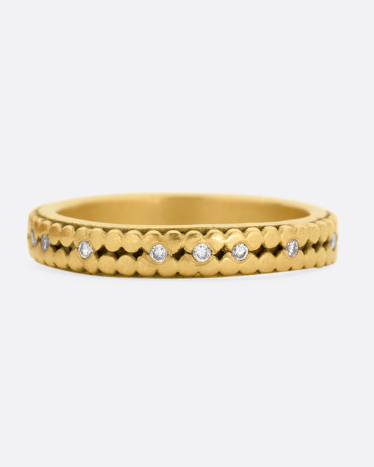 A yellow gold ring with two rows of dots and bezel set diamonds peppered along the center line. Shown from the front.