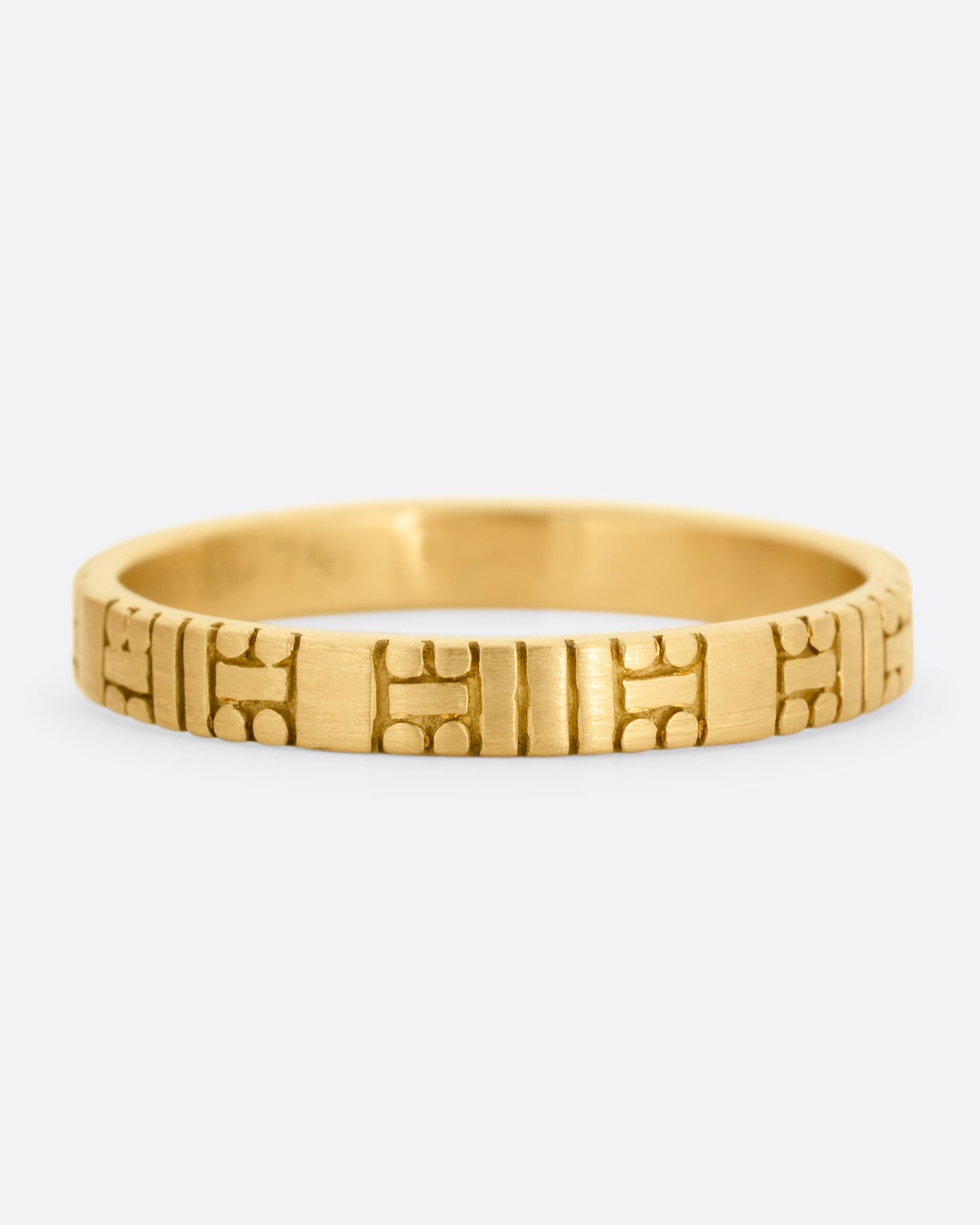 A yellow gold band with dots and dashes in a symmetrical pattern. Shown from the front.