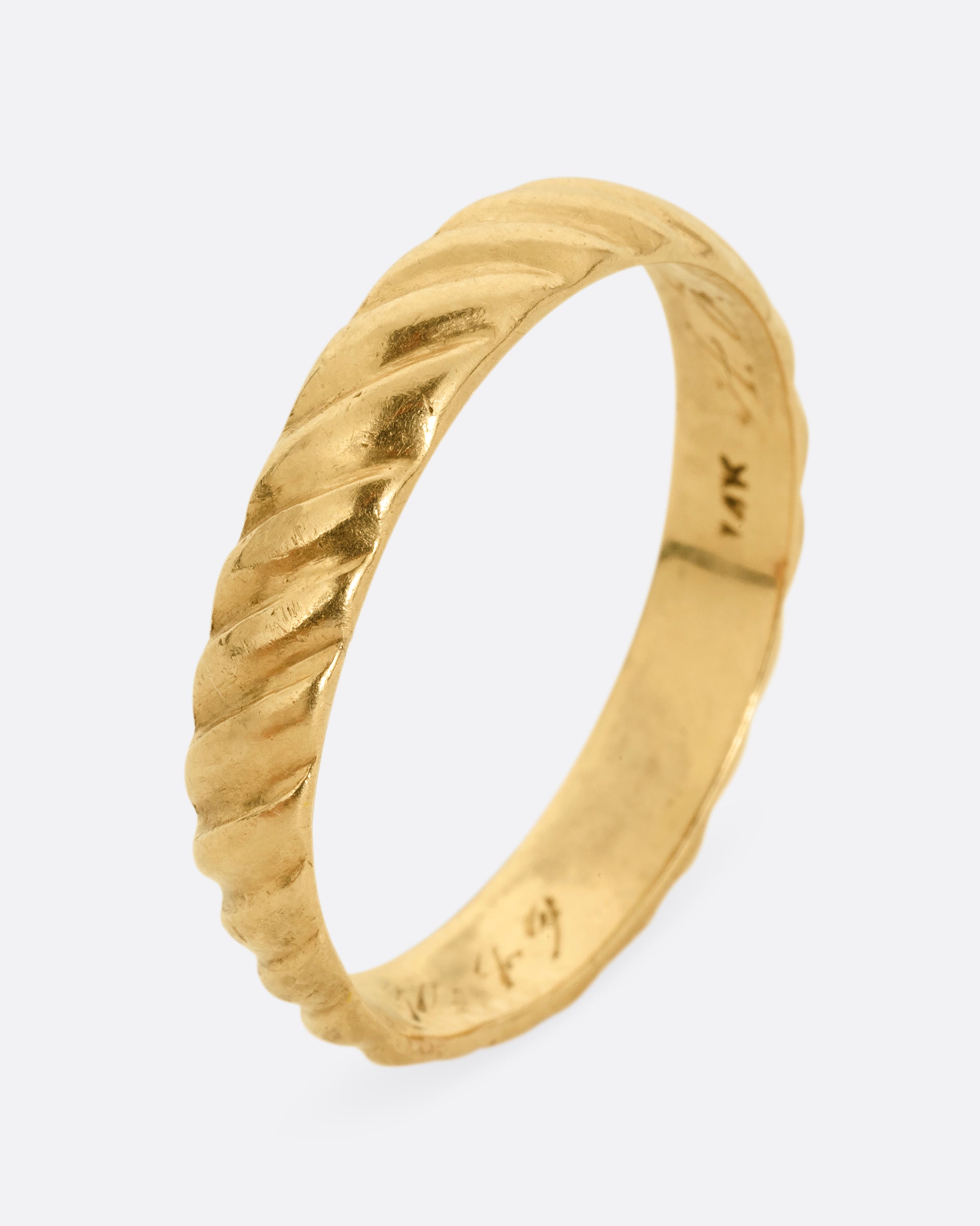 A yellow gold band with a continuous diagonal pattern. Shown standing up from the side.