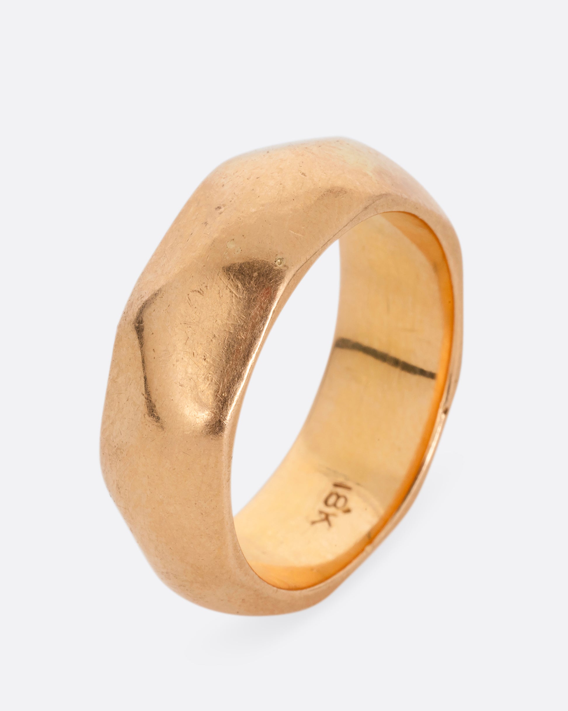 A wide hammered yellow gold cigar band. Shown standing up from the side.