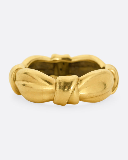 A yellow gold ring with bow knots throughout. Shown from the front.