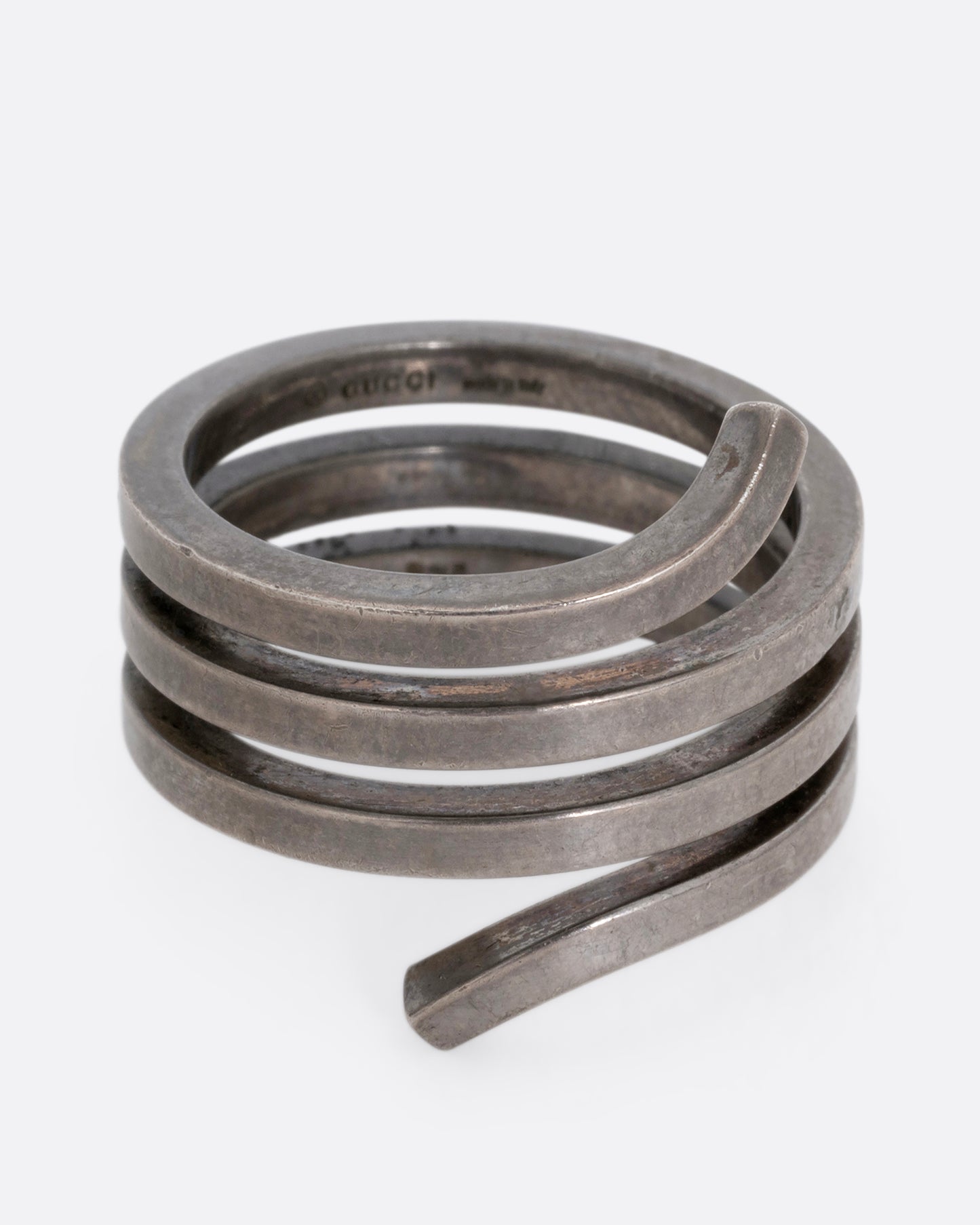 A silver ring with a coil silhouette. Shown from the front. 