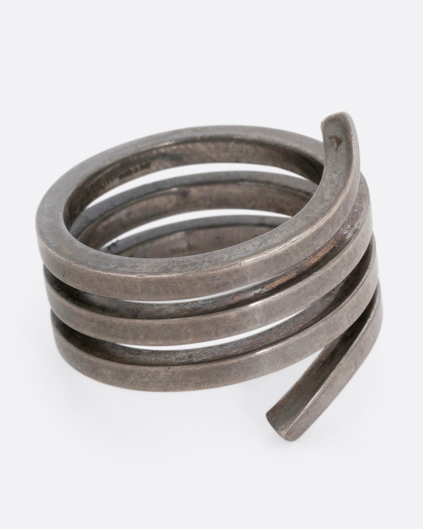 A silver ring with a coil silhouette. Shown from the side. 