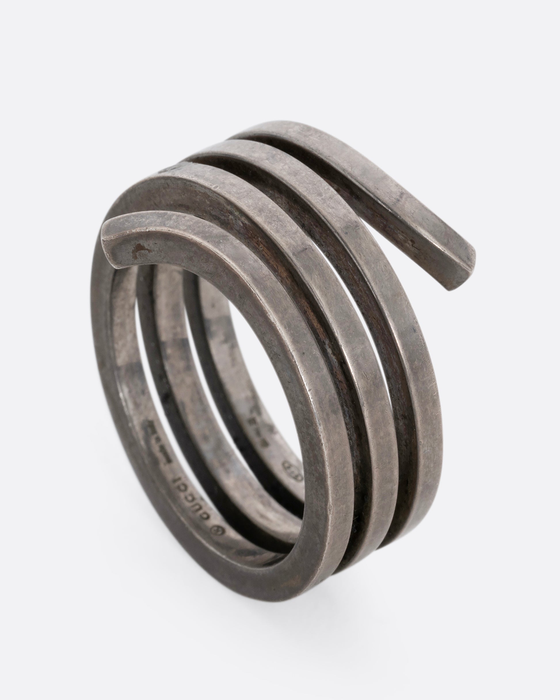 A silver ring with a coil silhouette. Shown standing up from the side. 