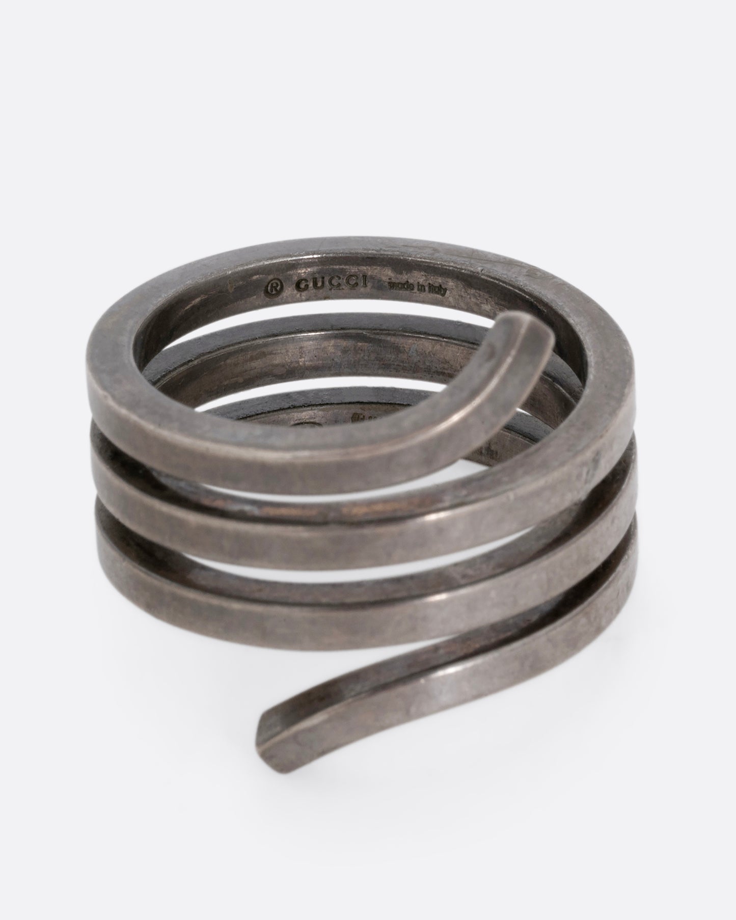 A silver ring with a coil silhouette. Shown from the front. 
