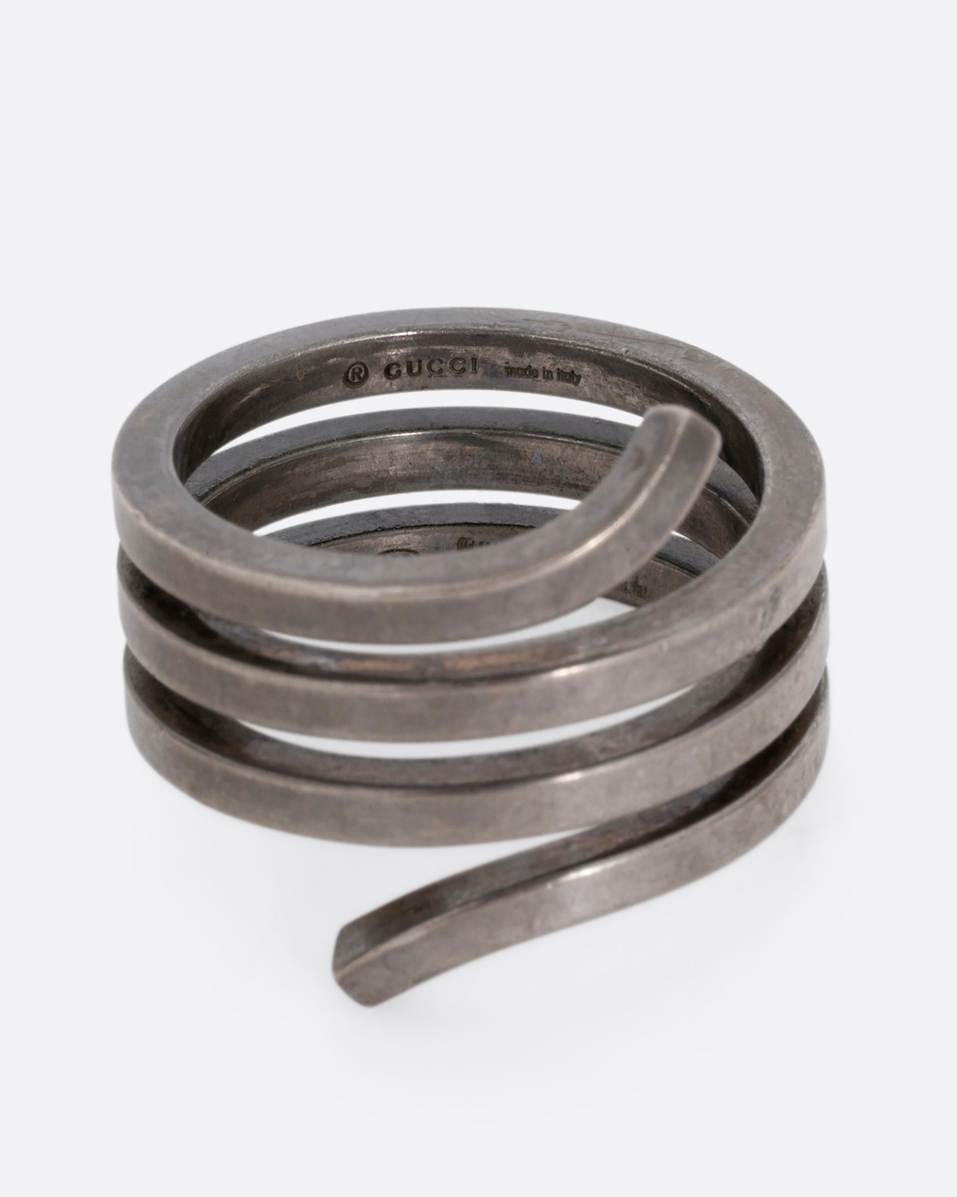 A silver ring with a coil silhouette. Shown from the front. 