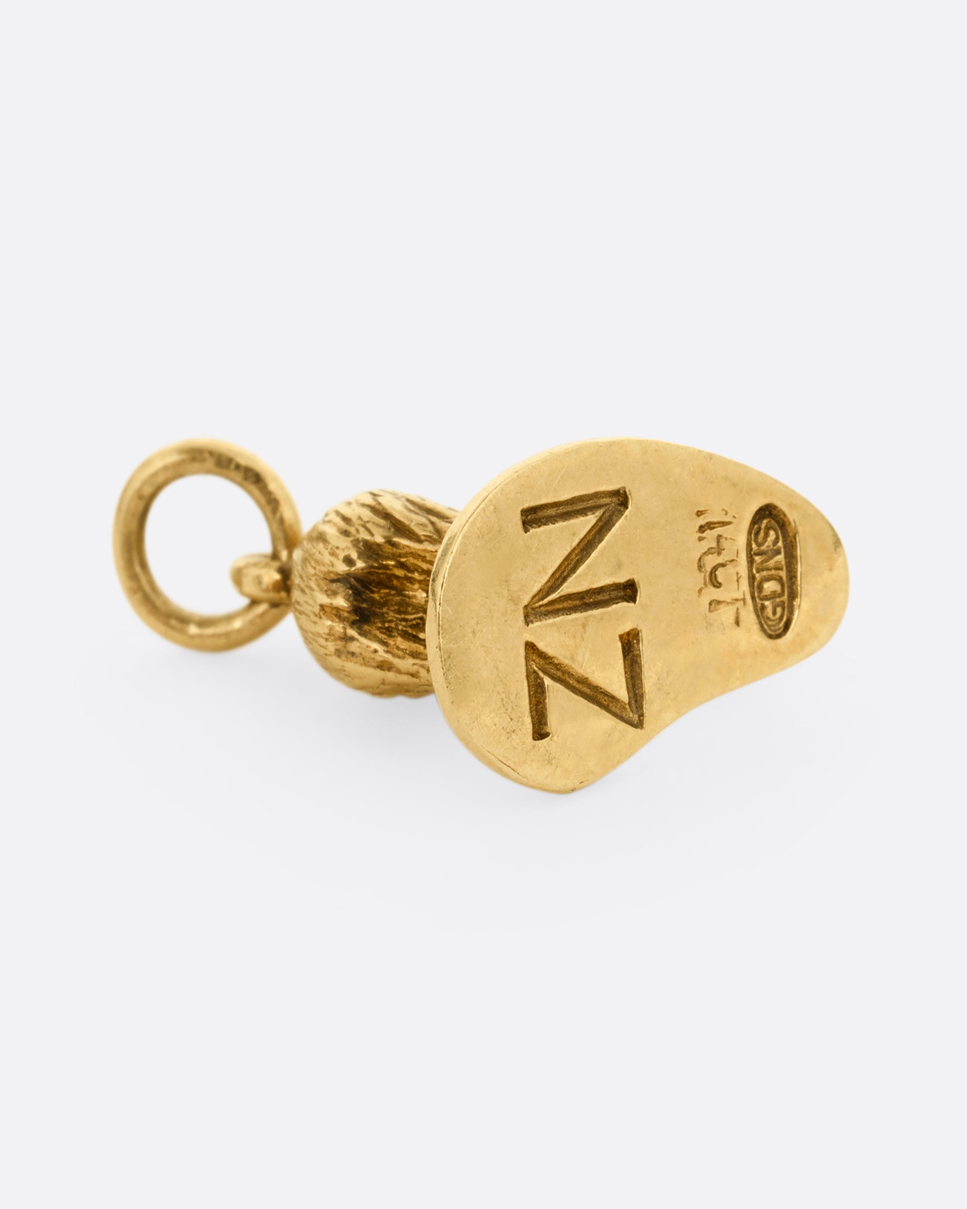 A yellow gold kiwi bird pendant with NZ on the bottom. Shown from the bottom.