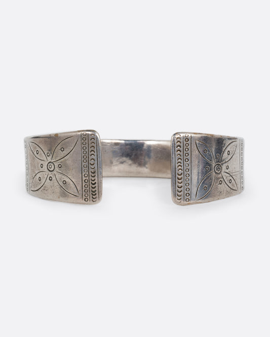 A silver bracelet with a graduated silhouette, hand stamped pattern, and opening in the front. Shown from the front.