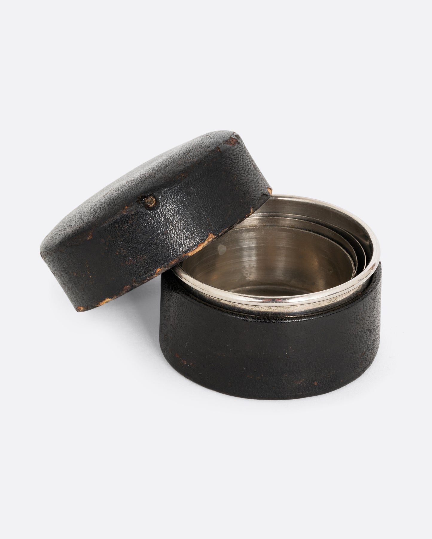 A silver  collapsable cup in a leather case. Shown open from the front.