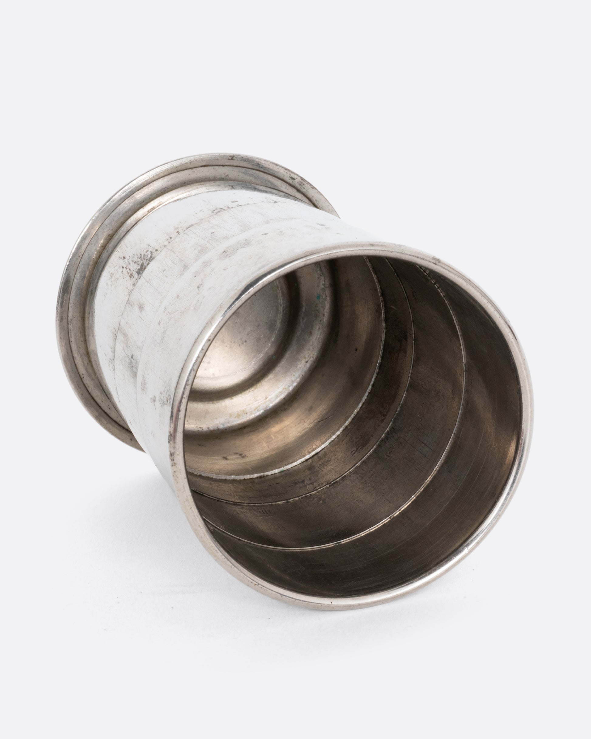 A silver collapsible cup shown on its side from the top.