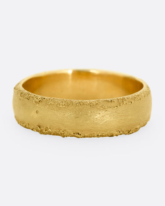A yellow gold band with a matte center and textured edges. Shown straight on.