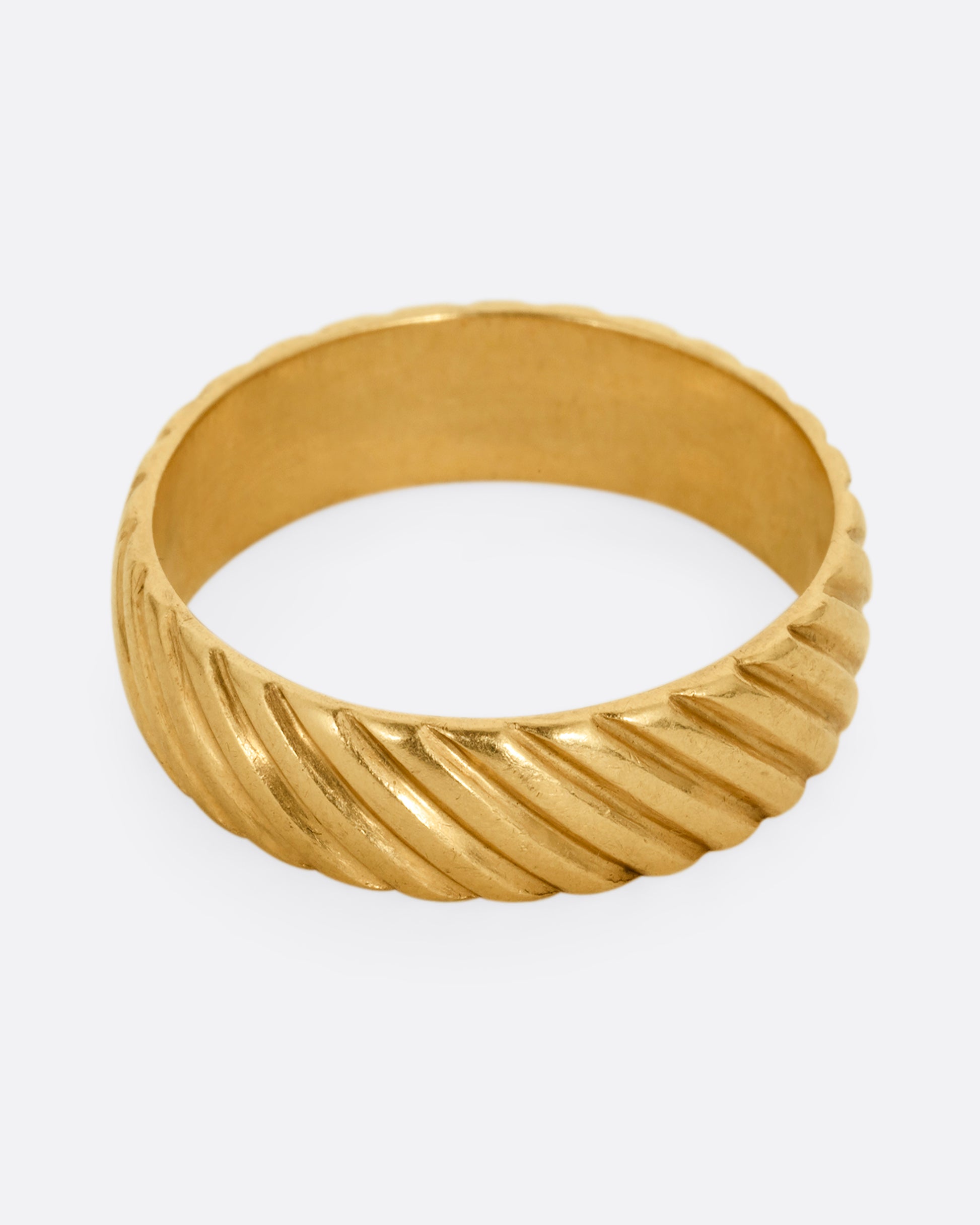 A wide yellow gold ring with an all over diagonal linear pattern. Shown from the front.