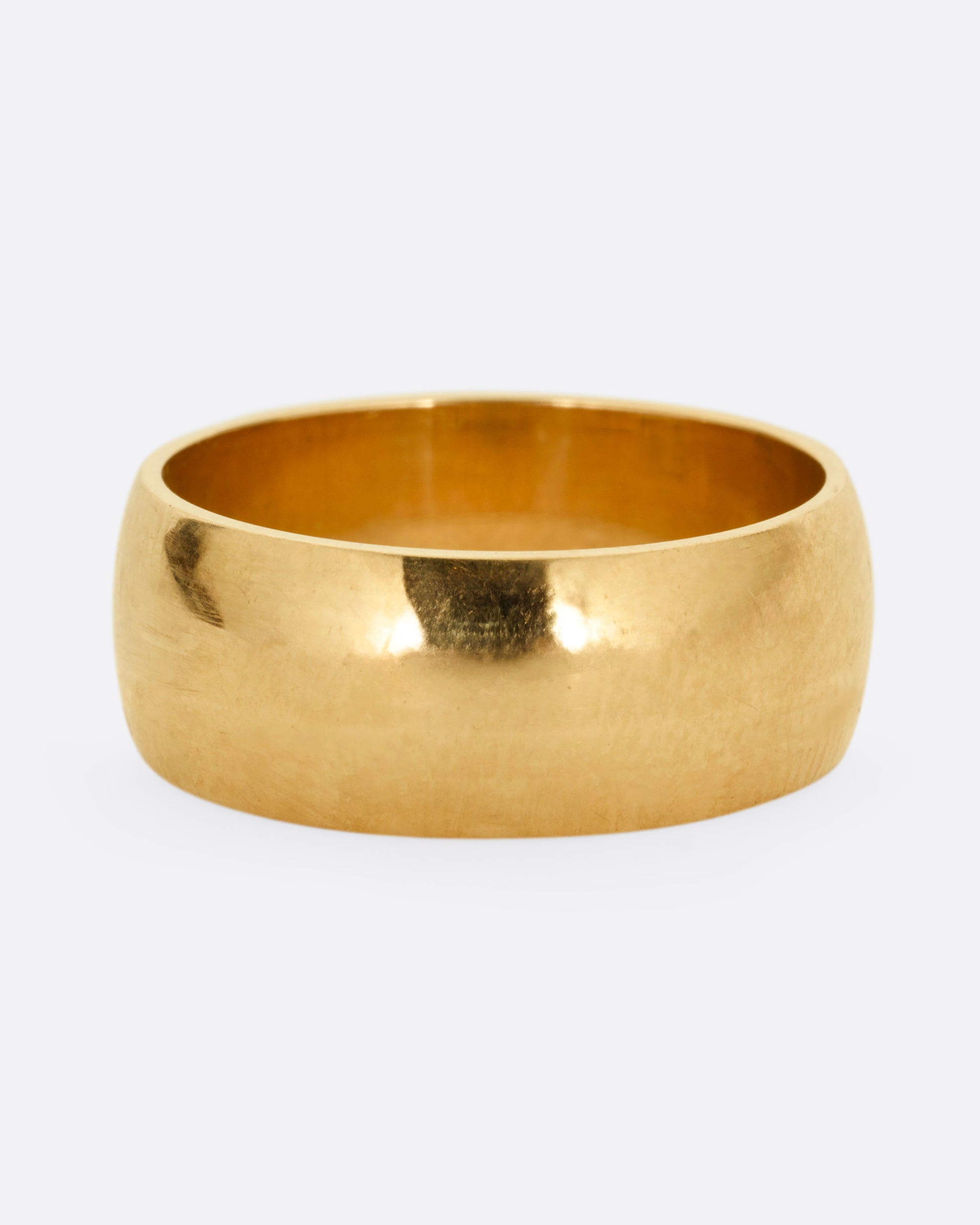 A broad yellow gold band with a rounded silhouette. Shown from the front. 