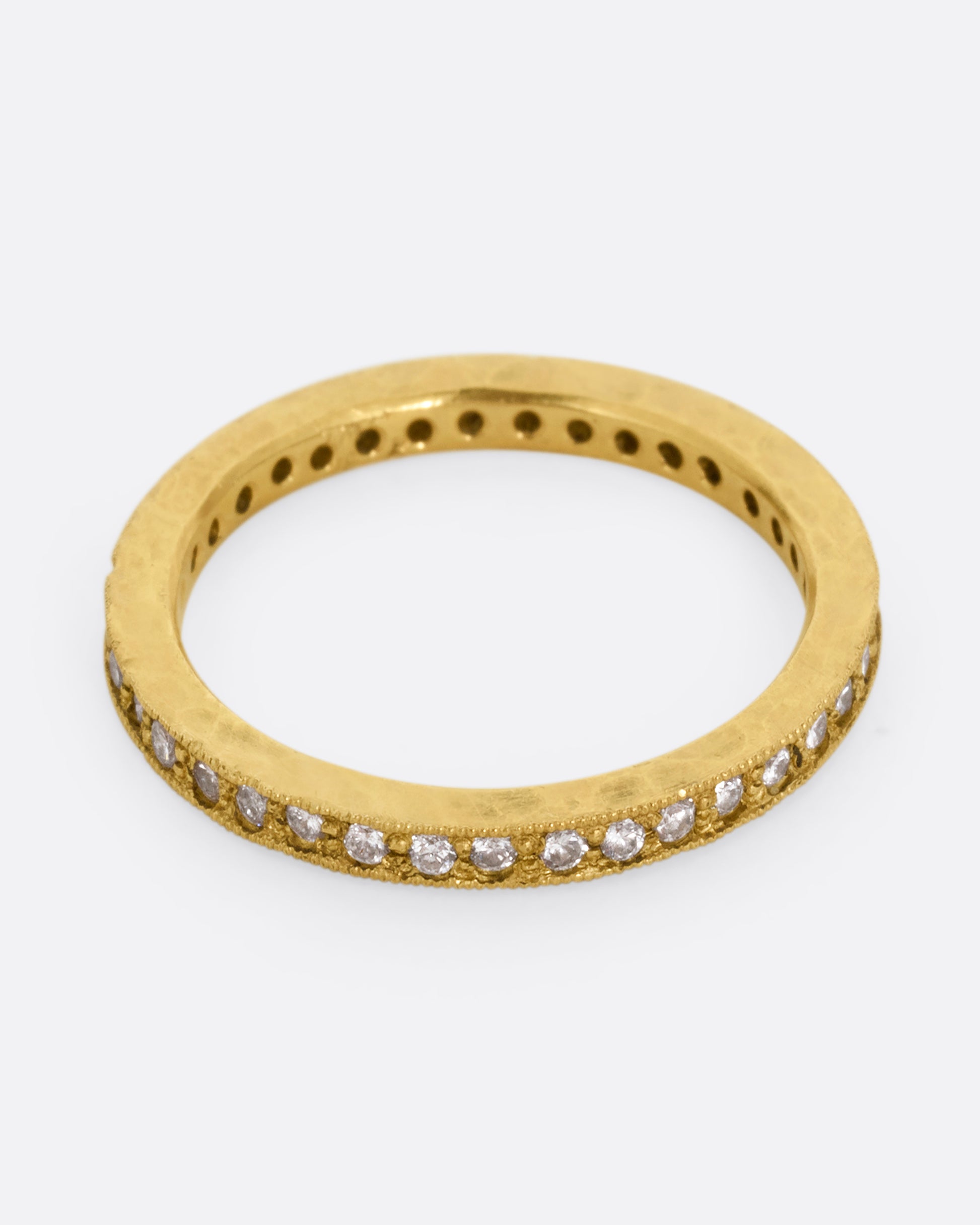 A yellow gold eternity band with bead set diamonds. Shown from the top.