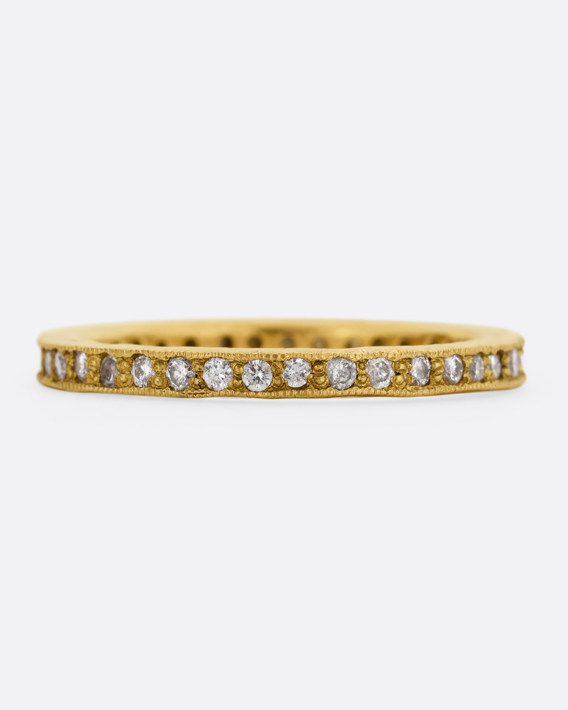 A yellow gold eternity band with bead set diamonds. Shown from the front.