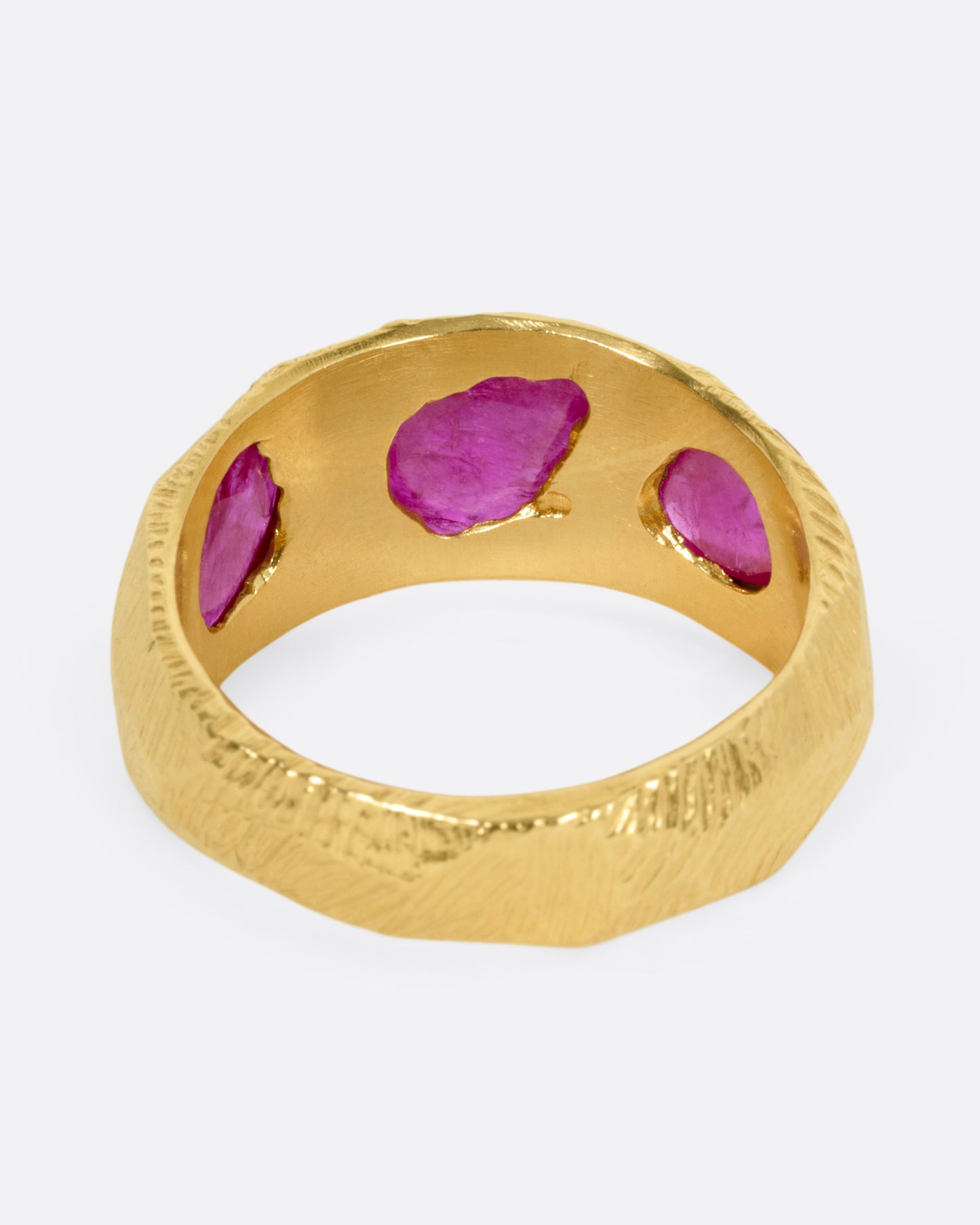 A yellow gold ring with three rubies, shown from the back.