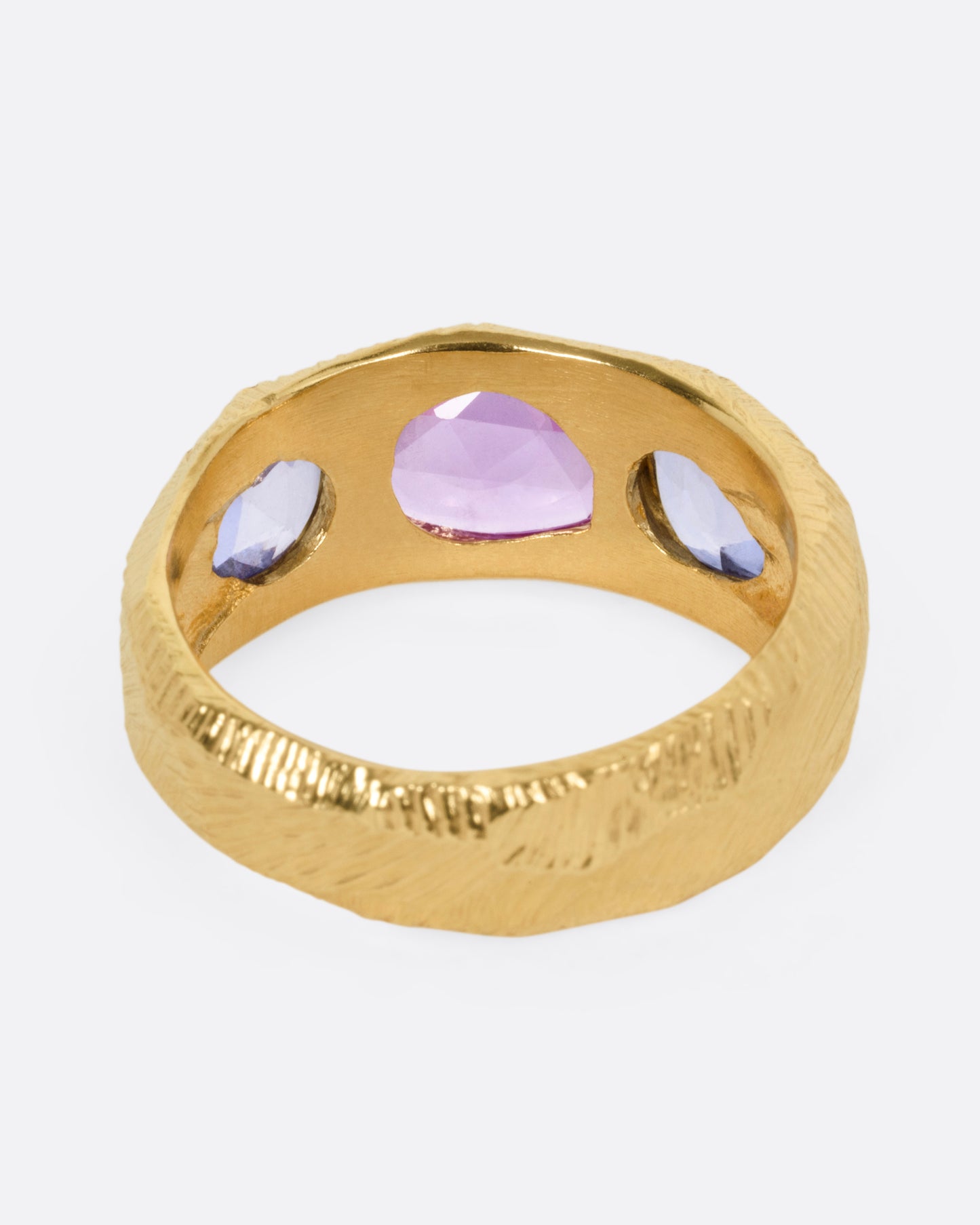 A yellow gold ring with two blue sapphires and one pink, shown from the back.