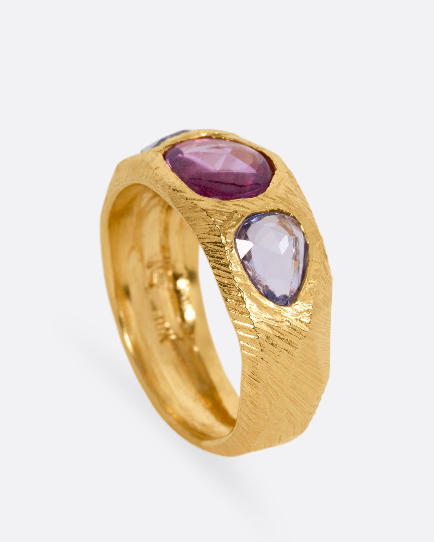 A yellow gold ring with two blue sapphires and one pink, shown from the side standing up.