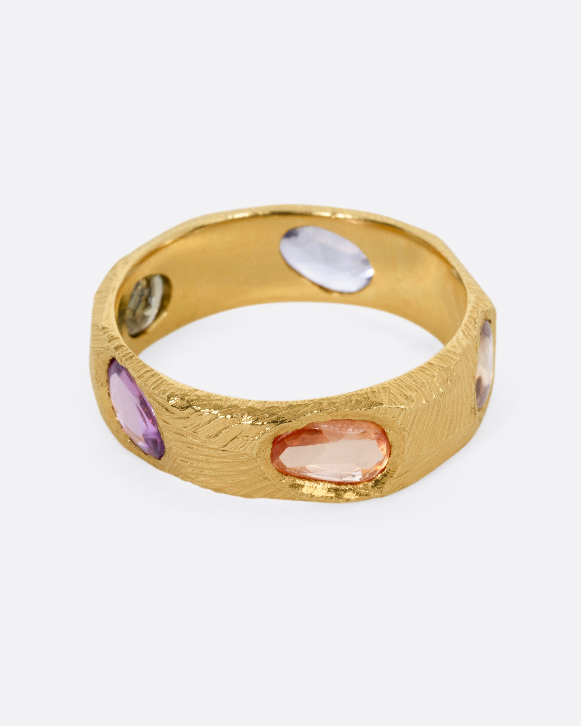 A yellow gold ring with multicolored rose cut sapphires, shown from the front.