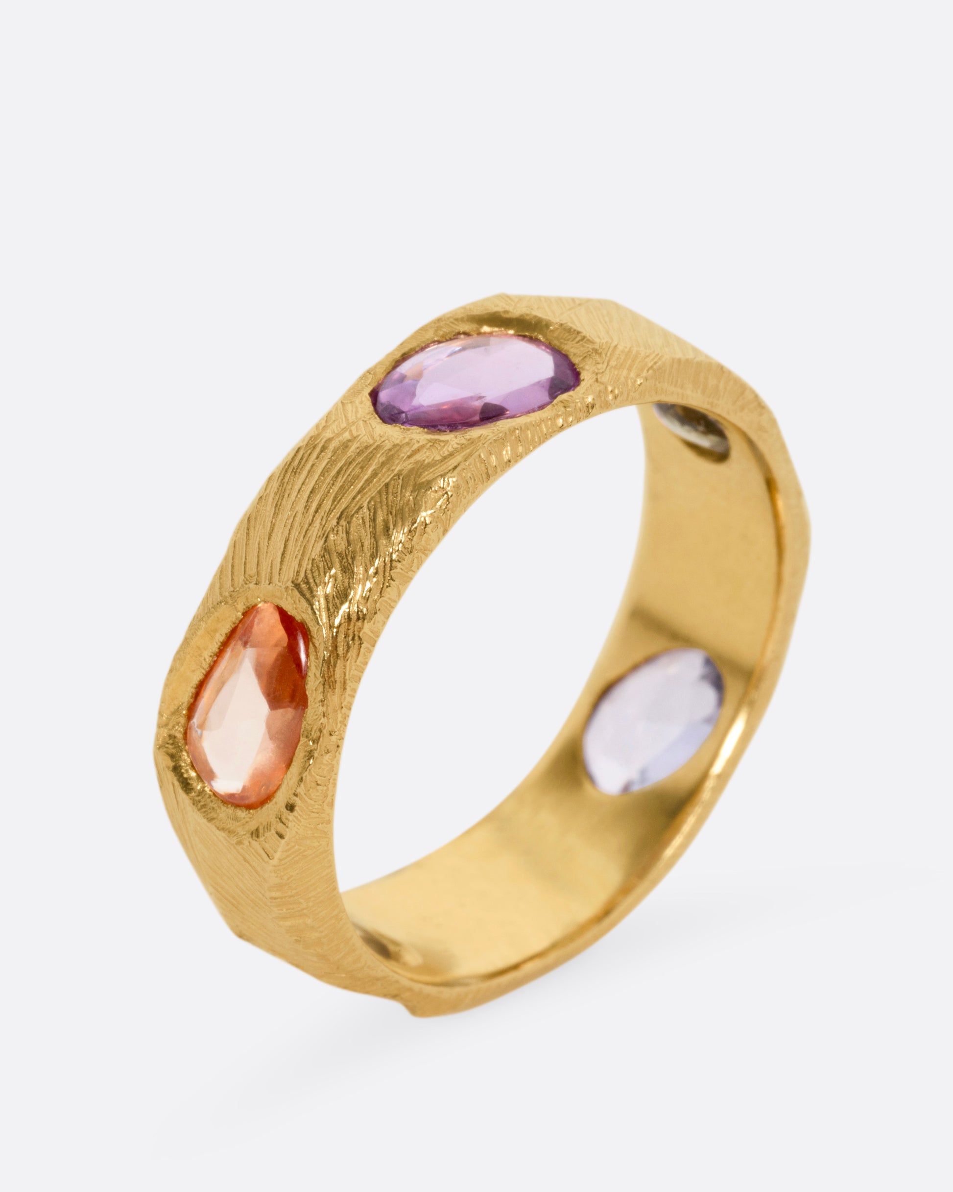 A yellow gold ring with multicolored rose cut sapphires, shown from the side standing up.