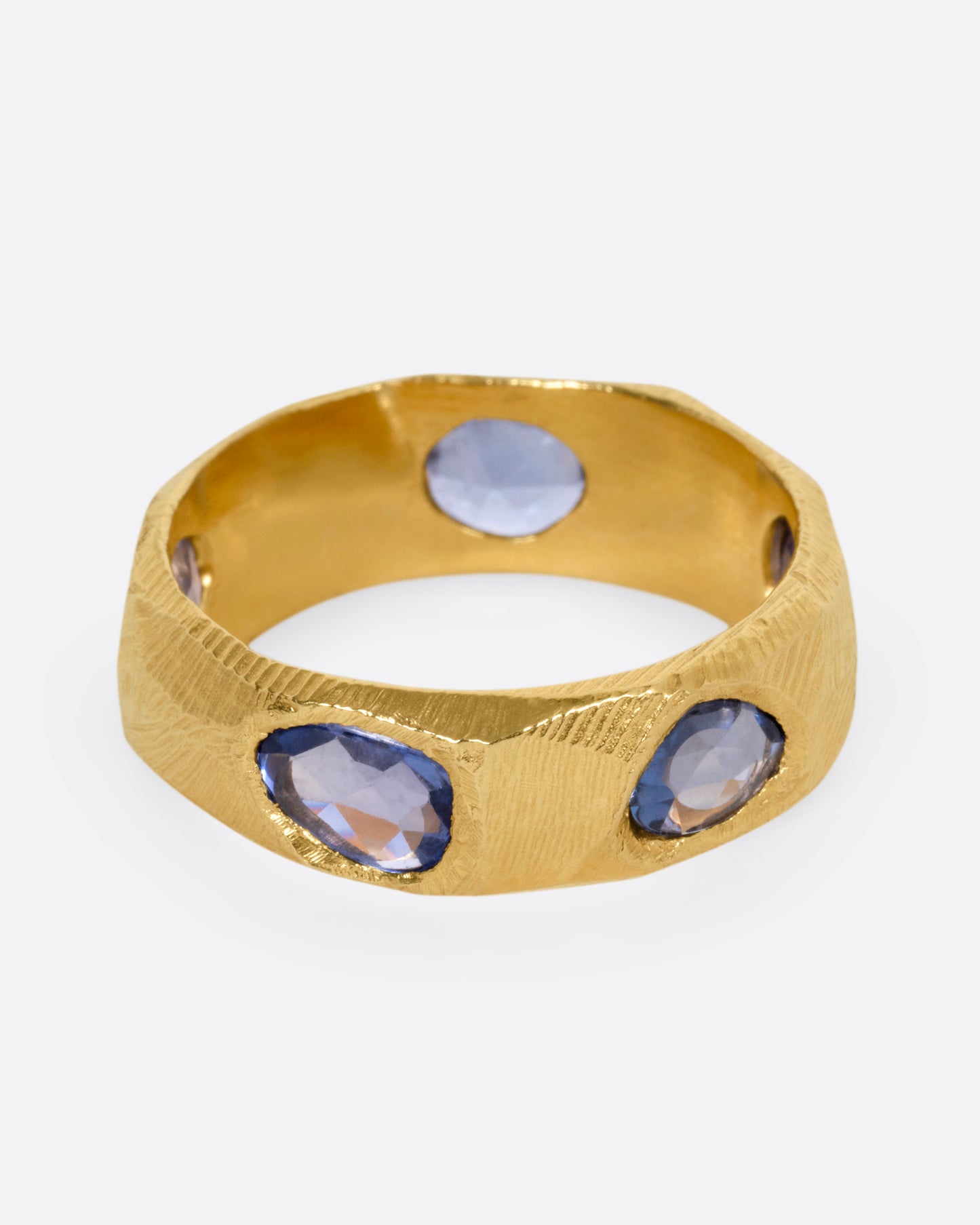A yellow gold ring with five blue sapphires, shown from the front.
