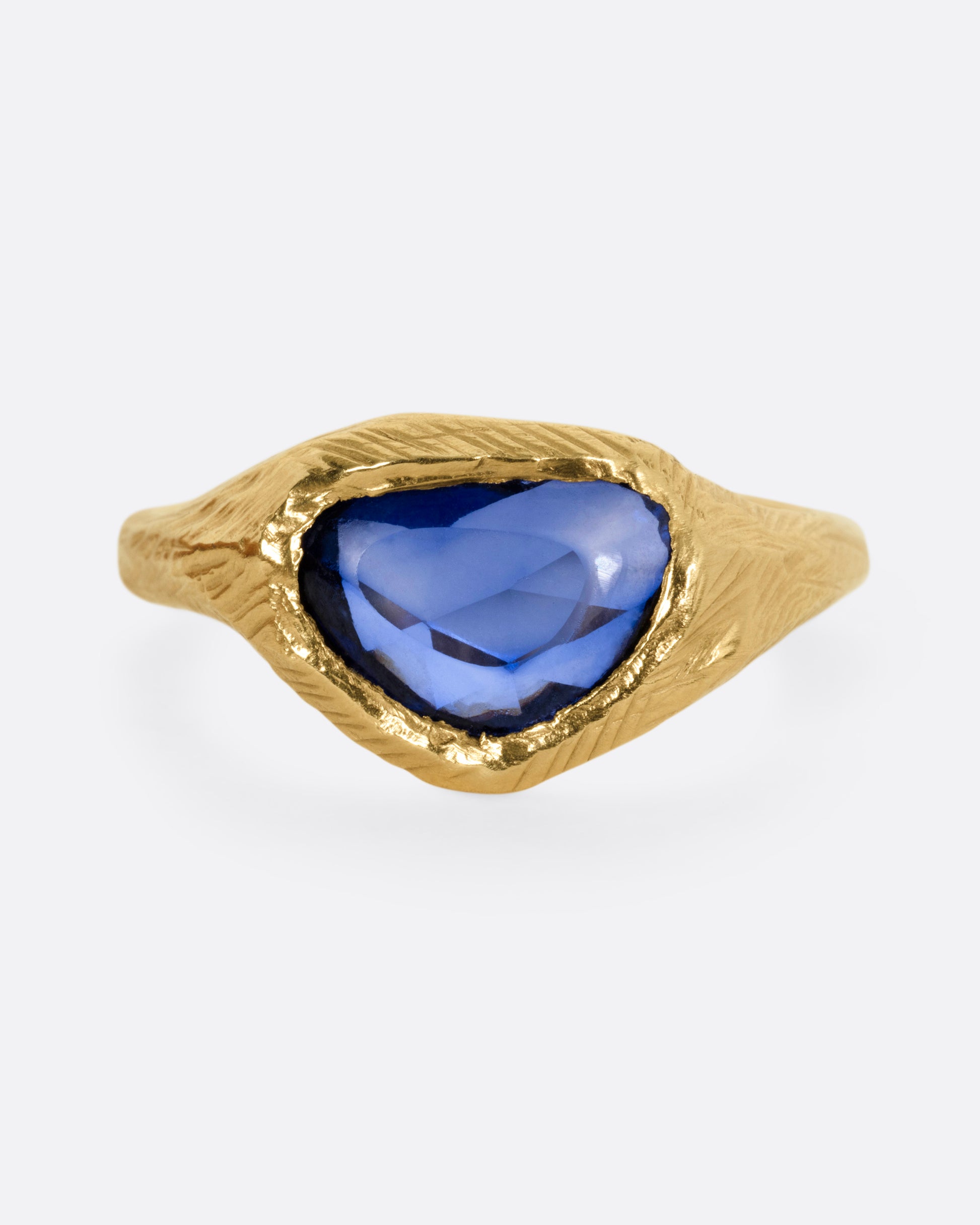A yellow gold ring with a blue sapphire, shown from the front.