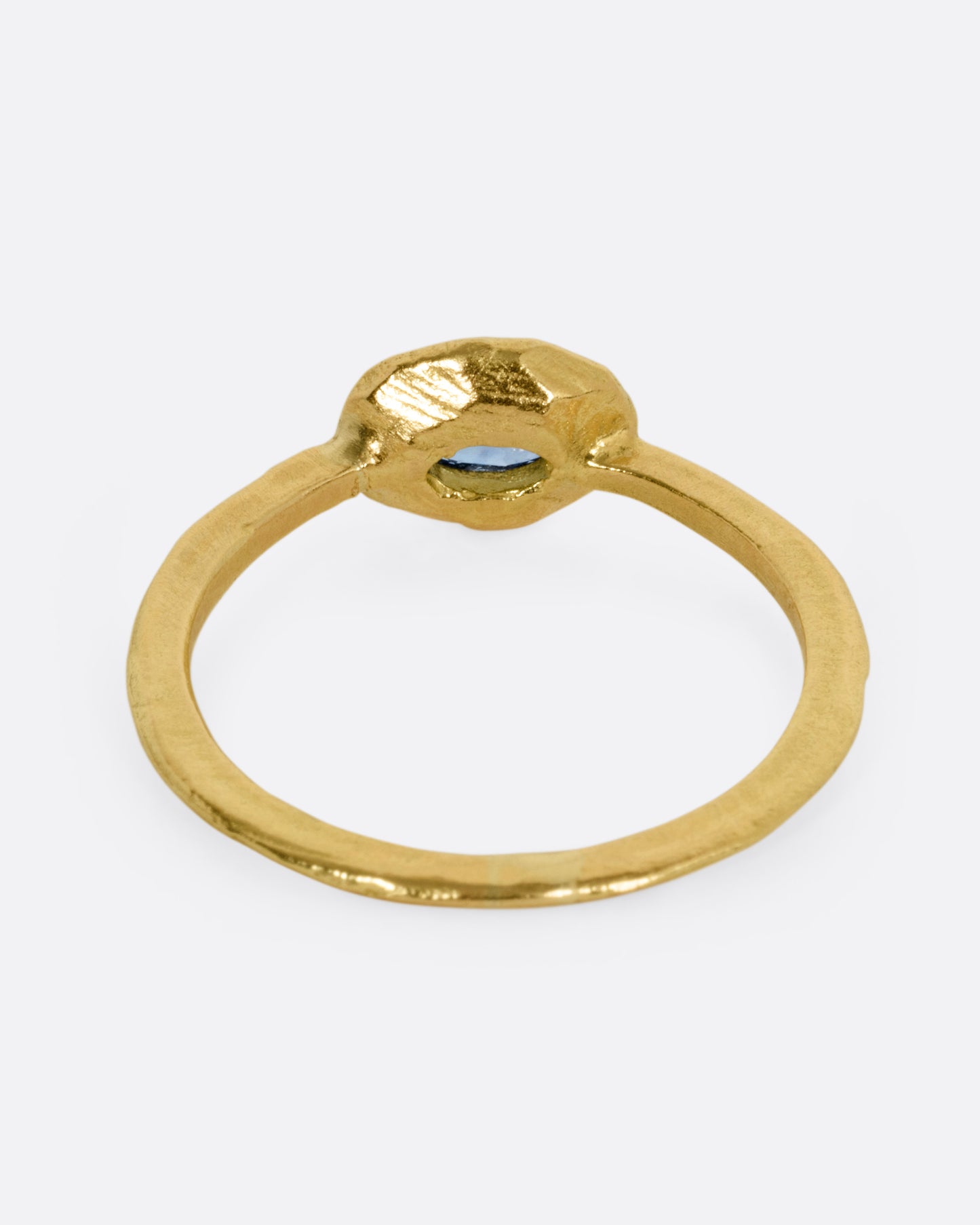 A yellow gold ring with a blue sapphire, shown from the back.