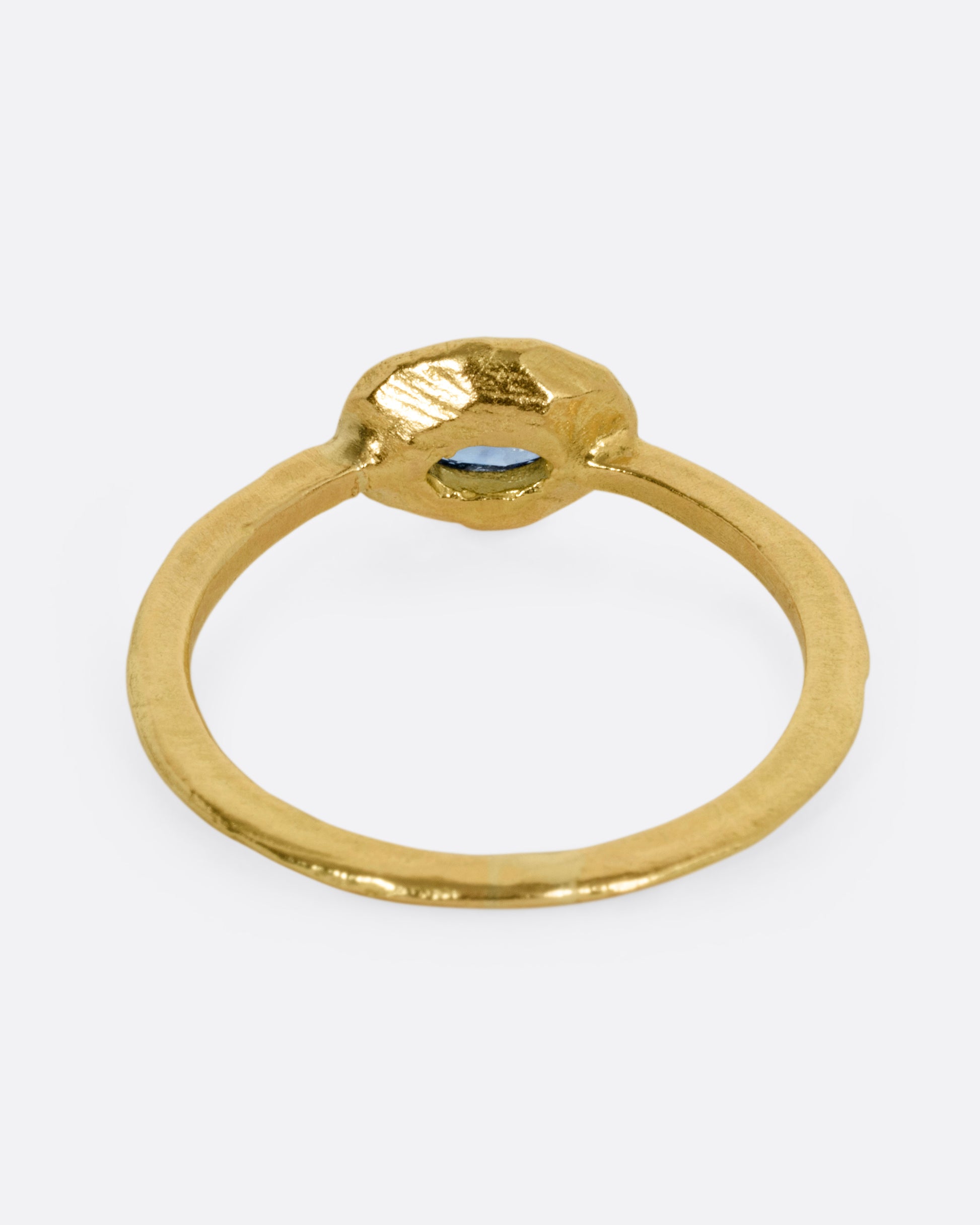 A yellow gold ring with a blue sapphire, shown from the back.