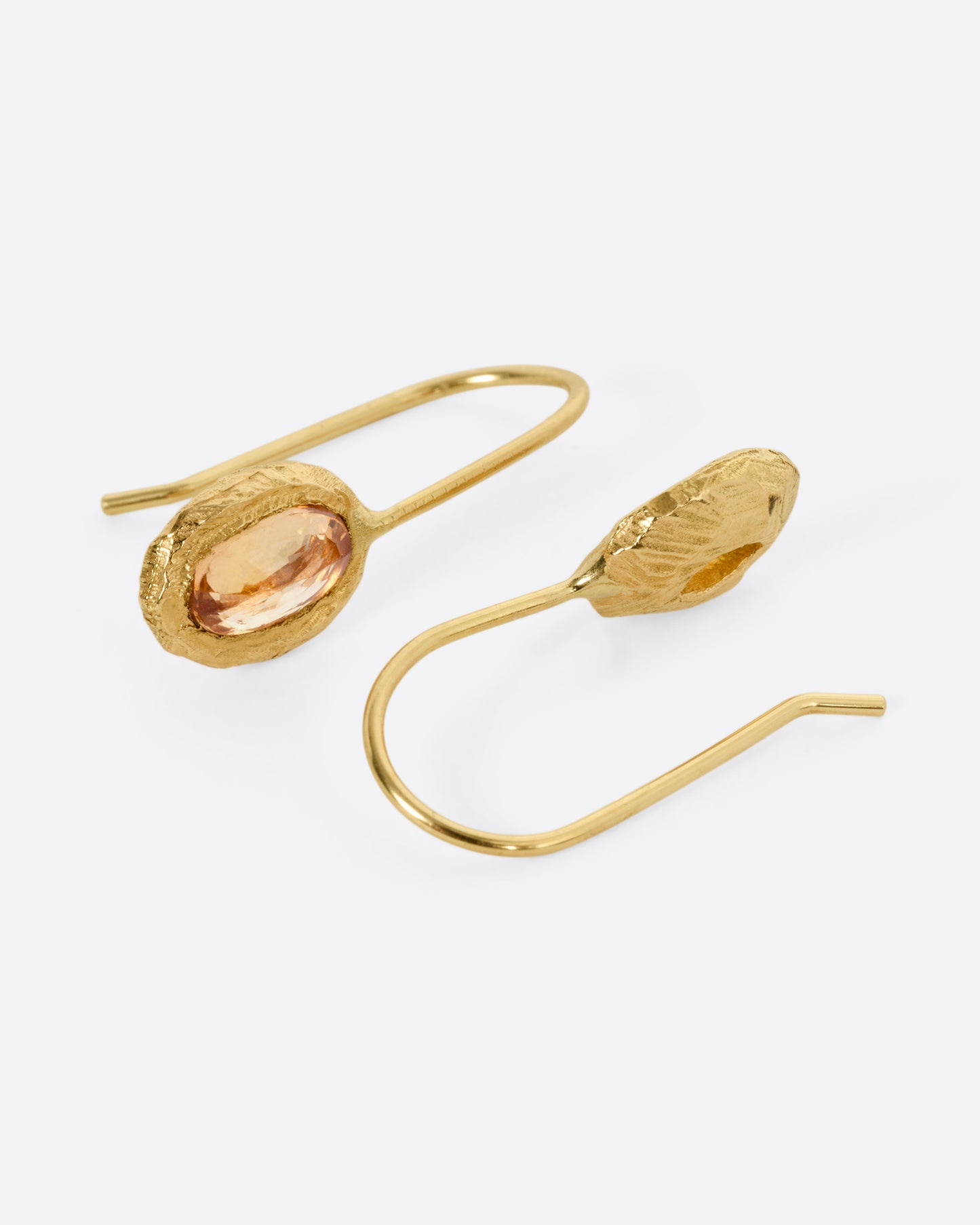 A pair of yellow gold earrings with yellow sapphires, shown from the side.