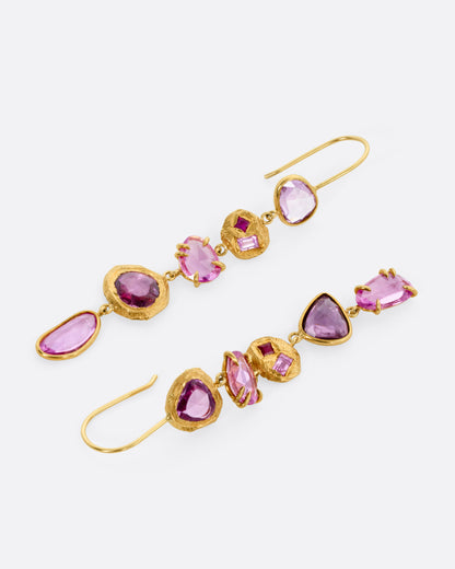 A pair of yellow gold drop earrings with pink sapphires and ruby and diamond accents, shown lying flat from the front.